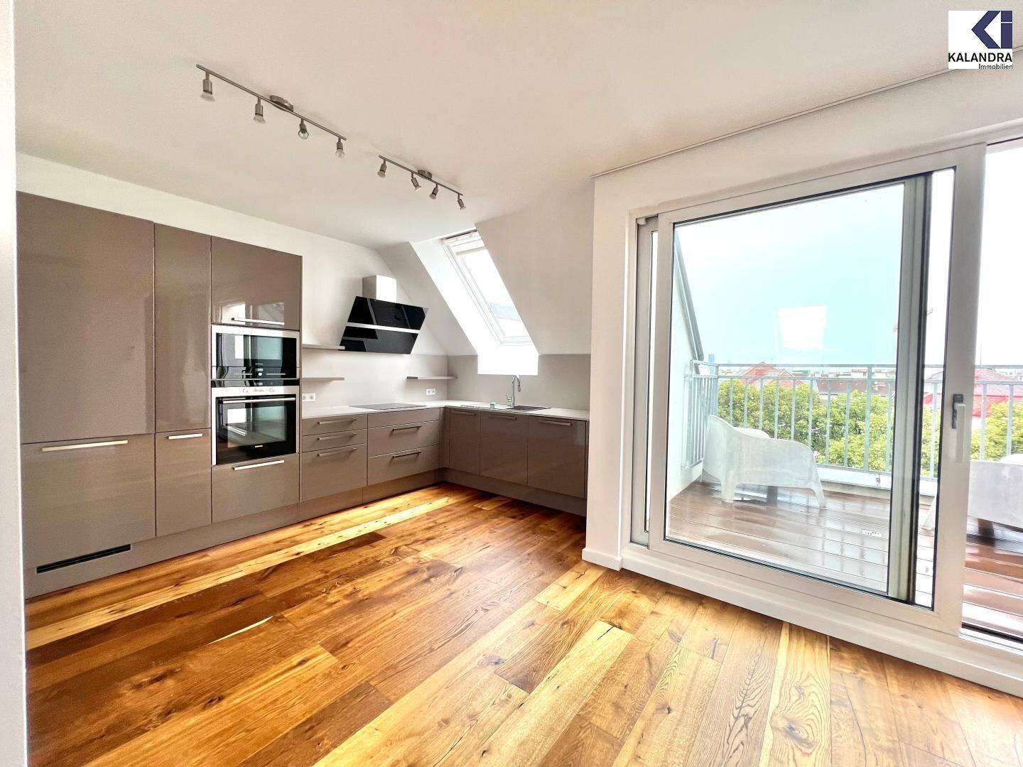 Moderne Küche mit glänzenden Schränken, Holzboden und Zugang zu einer Terrasse im Dachgeschoss.