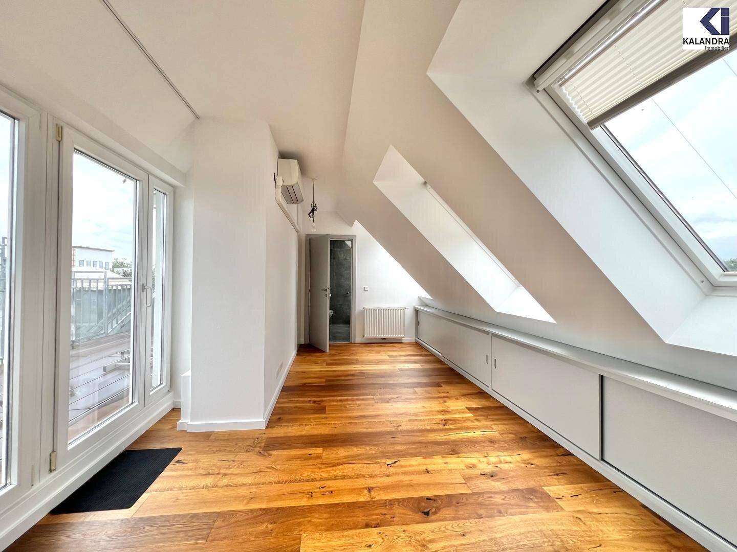 Geräumiger Dachgeschossraum mit Holzboden, mehreren Dachfenstern und integrierten Stauschränken.