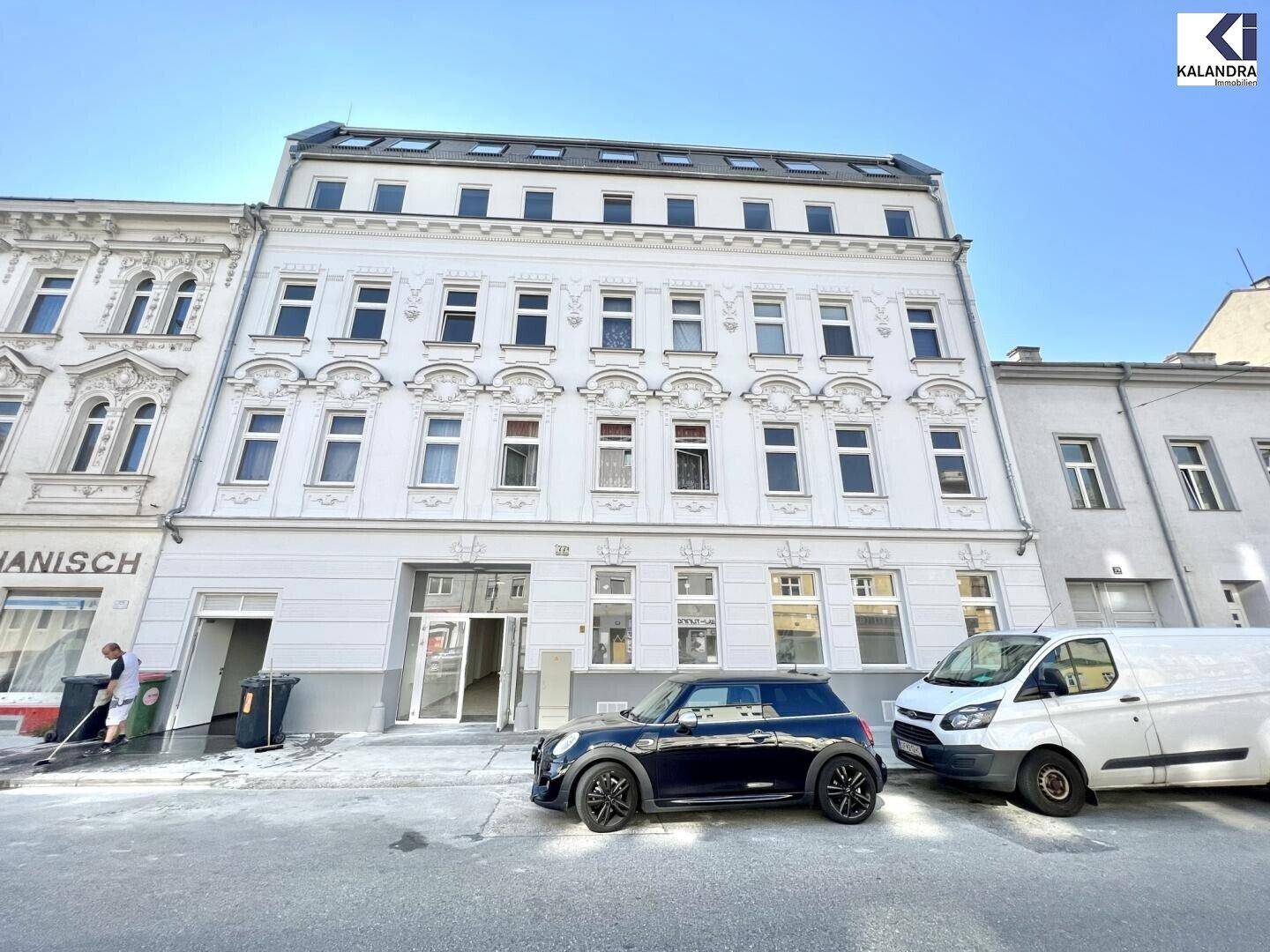 Ansicht der historischen Gebäudefassade von der Straße aus mit parkenden Autos.