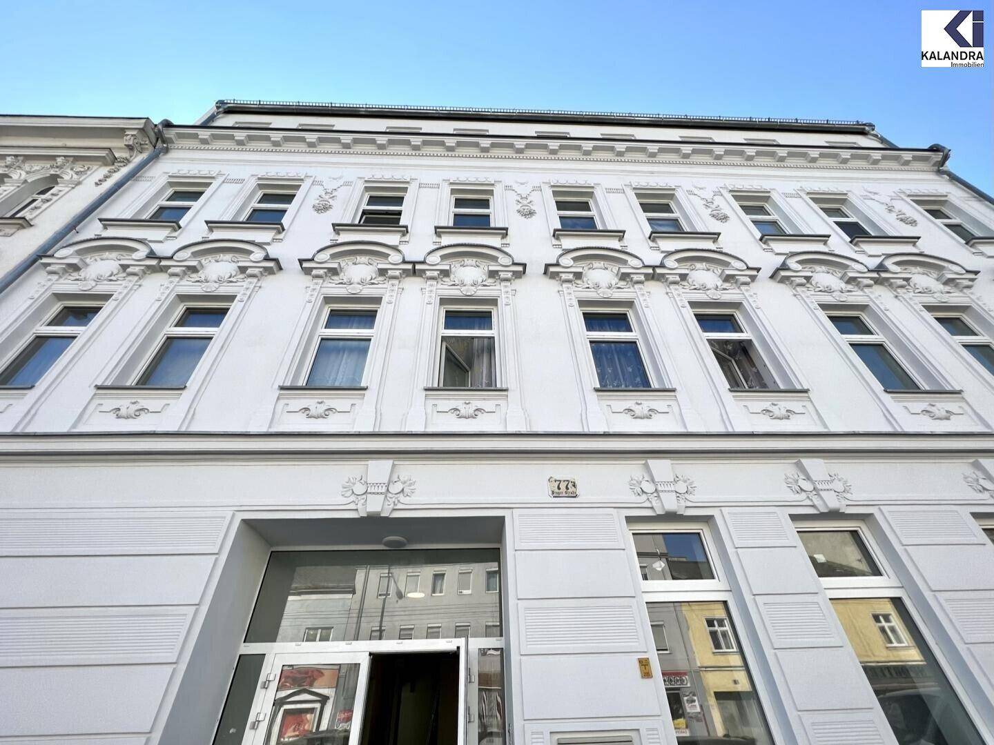 Historische weiße Fassade eines Altbaus mit dekorativen Fensterrahmen und Verzierungen.
