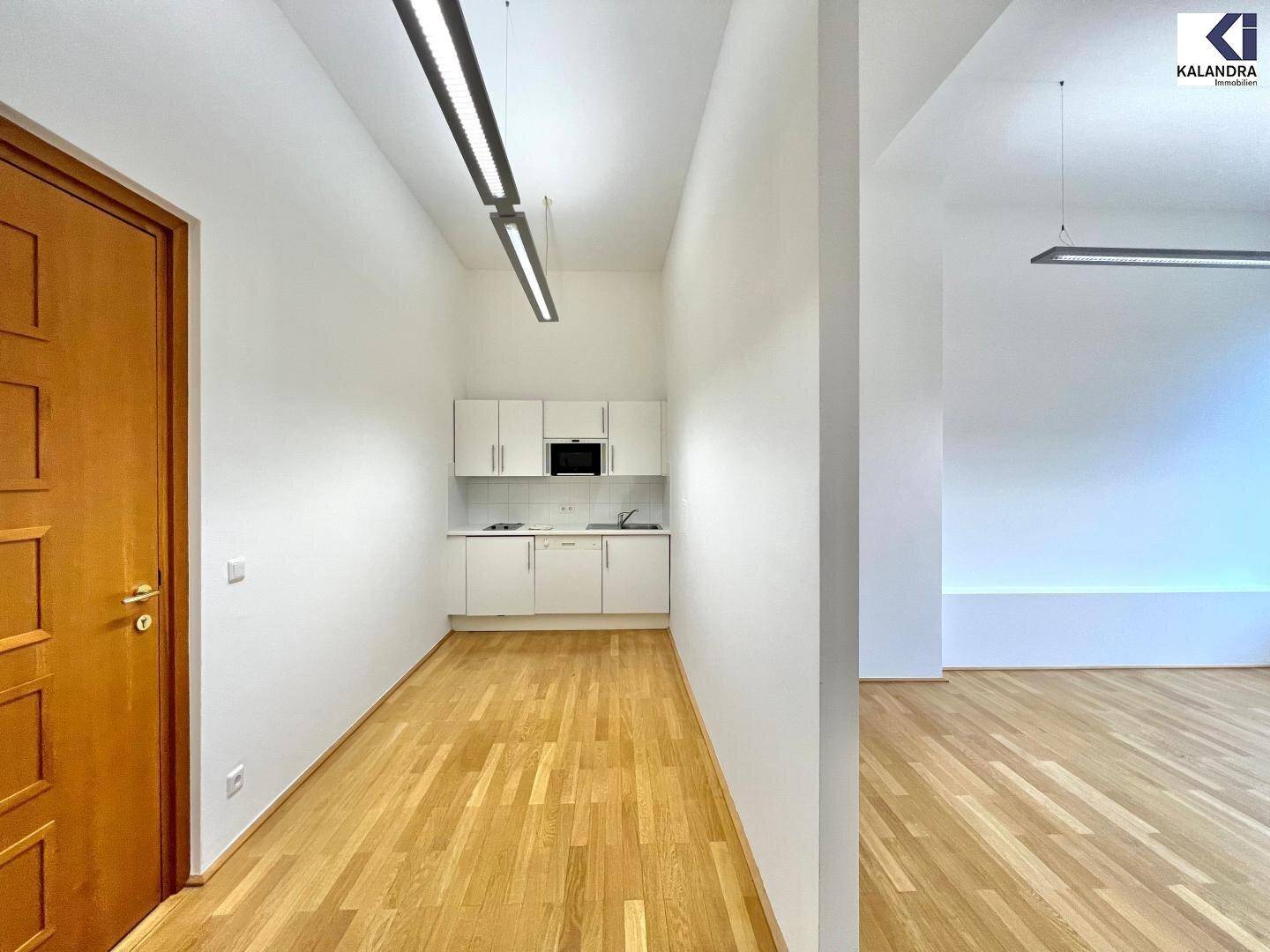 Heller Raum mit moderner Küchenzeile, Holzboden und weiß gestrichenen Wänden.