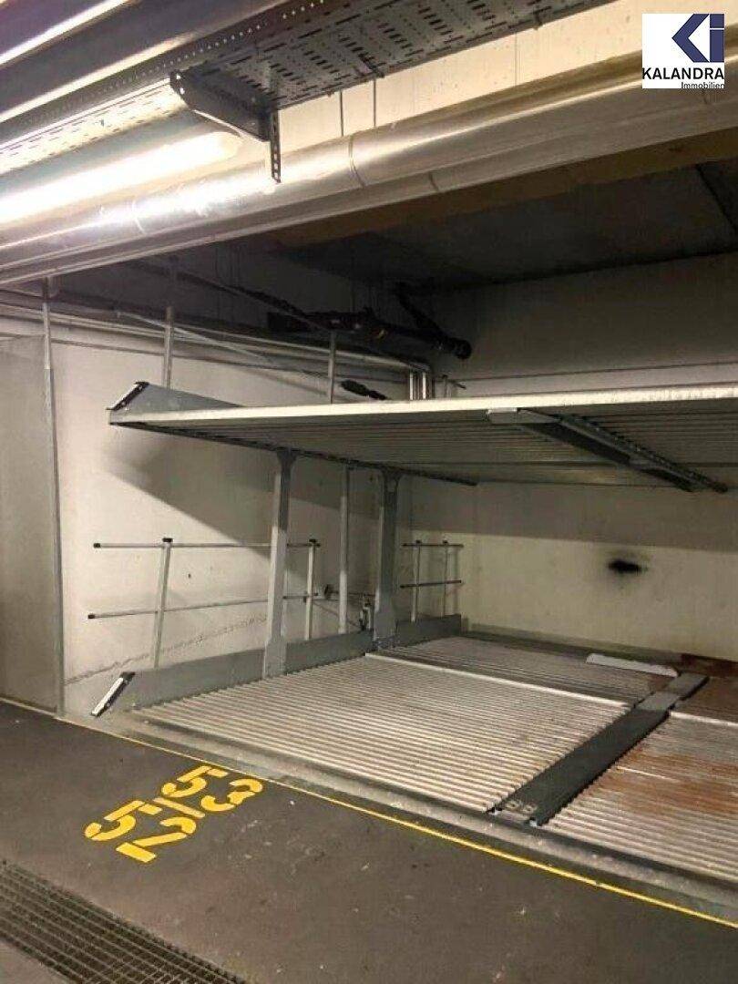 Tiefgarage mit Doppelparker-System für zwei Fahrzeuge und sichtbaren Installationen an der Decke.