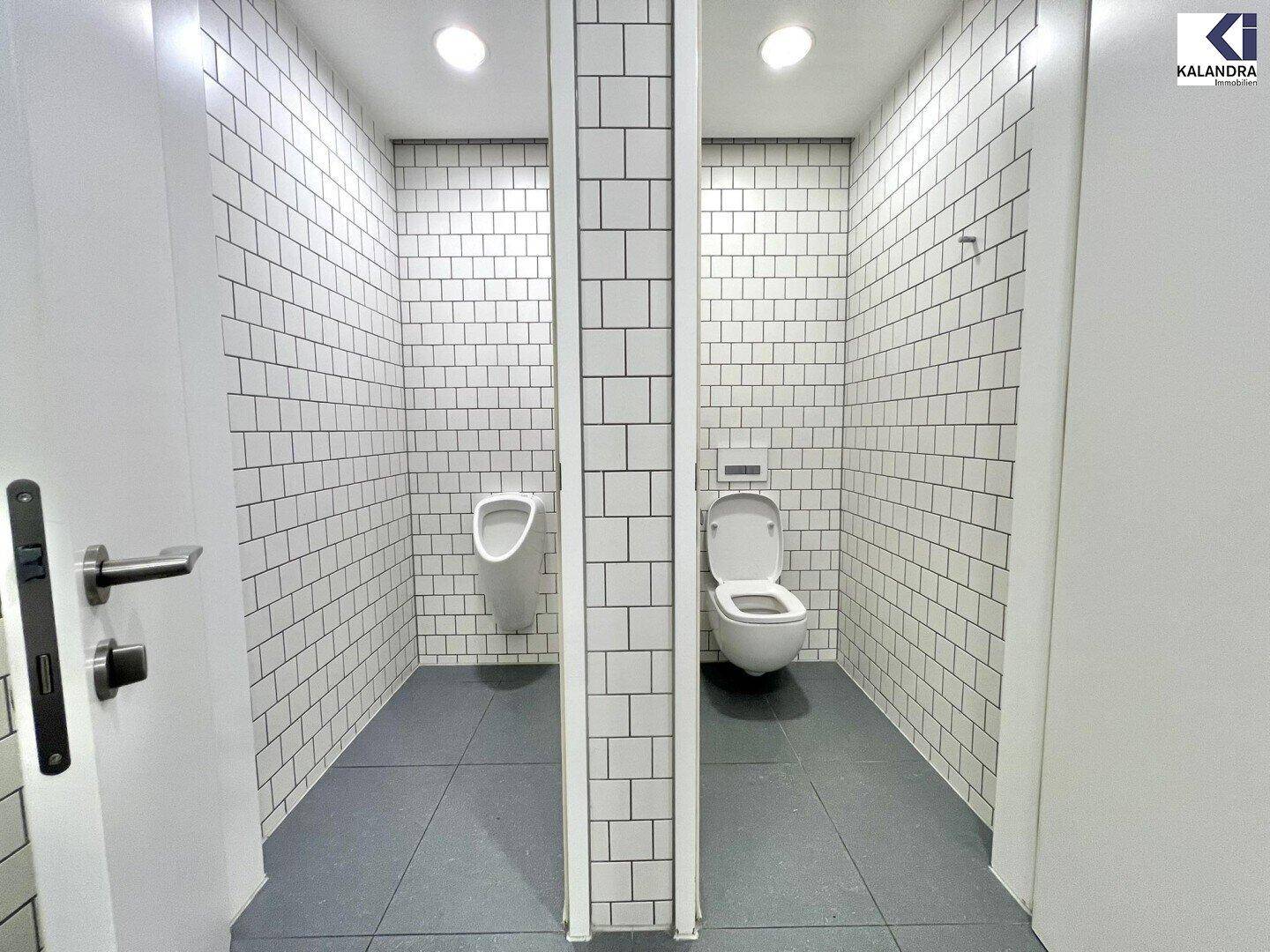 Zwei separate Toilettenkabinen mit weißen Fliesen und modernen Sanitäranlagen.