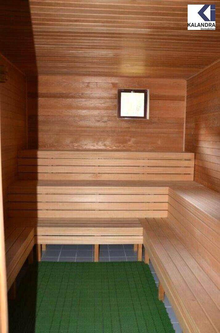 Innenansicht einer Holzsauna mit mehreren Bänken und einem kleinen Fenster, bereit zur Nutzung.