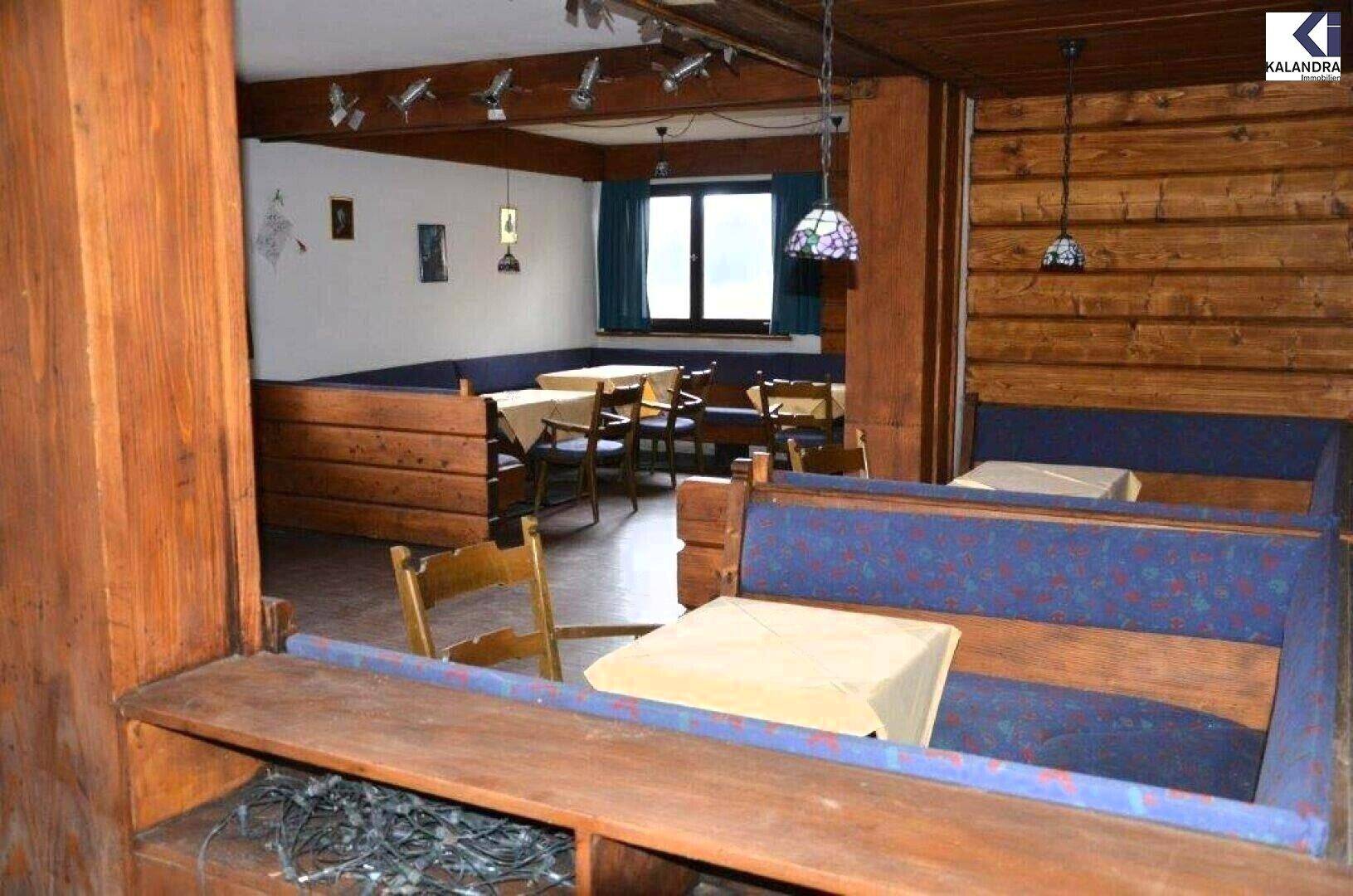 Essbereich mit Holzbänken, blauer Polsterung und Tischen, umgeben von Holztäfelung und einer Holzdecke.