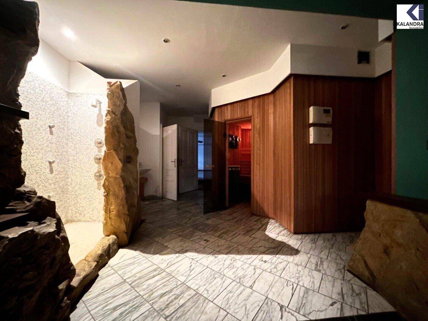 Wellnessbereich mit Sauna, Dusche und gefliestem Boden in modernem Design.
