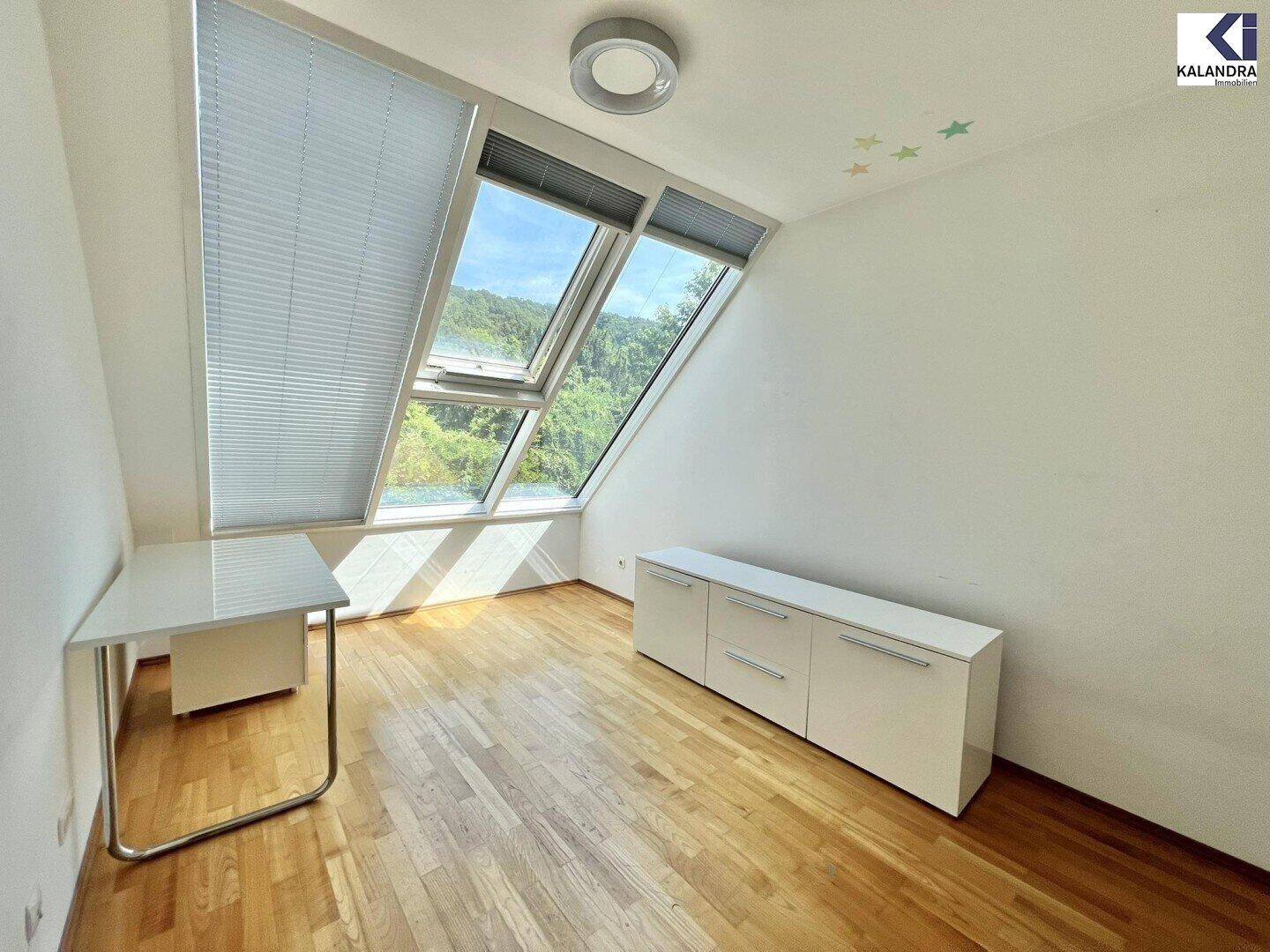 Modern eingerichtetes Zimmer im Dachgeschoss mit Schreibtisch und Schrank, ideal als Arbeits- oder Kinderzimmer.