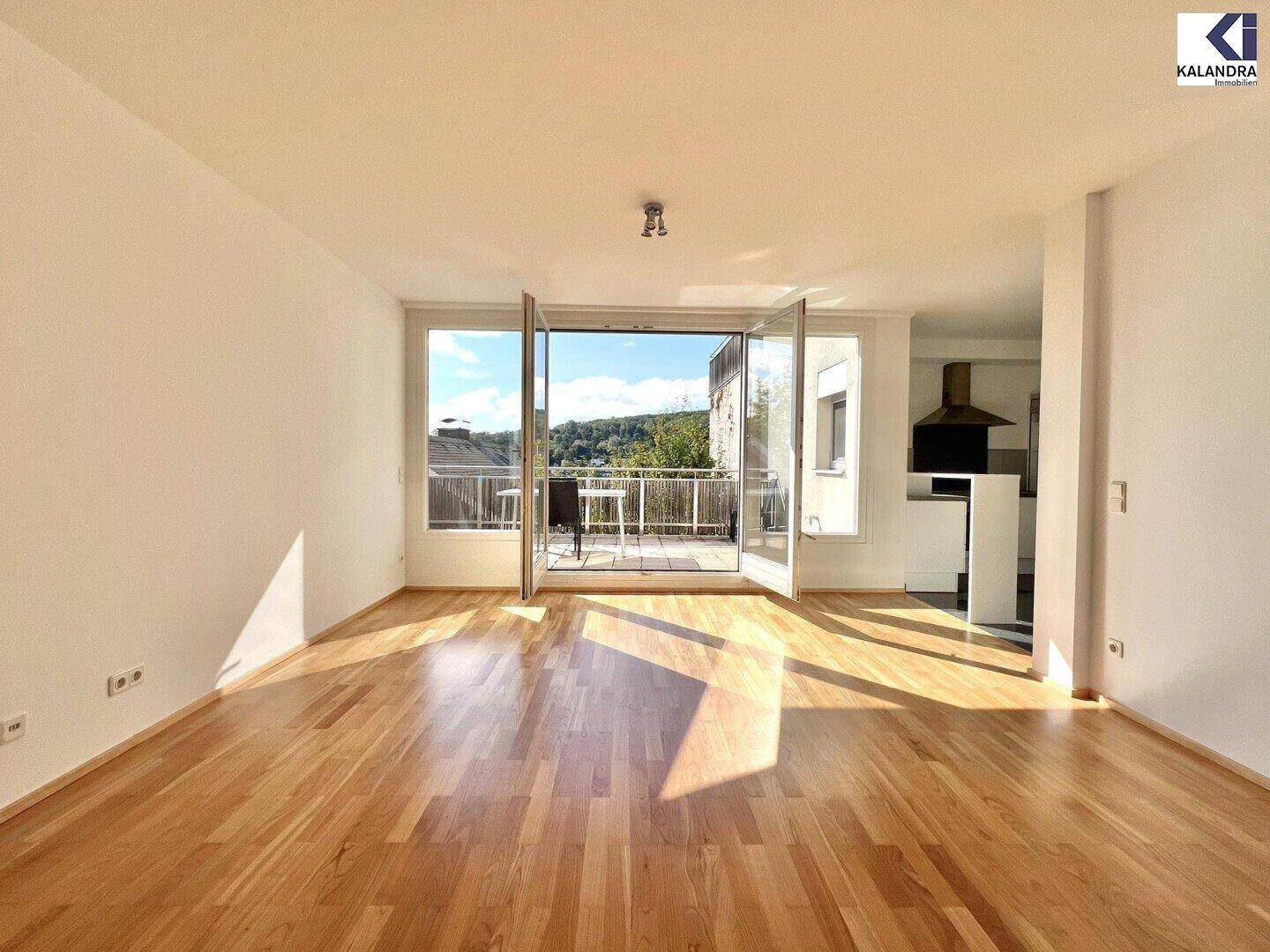 Helles Wohnzimmer mit Parkettboden und Zugang zu einem Balkon mit schöner Aussicht.