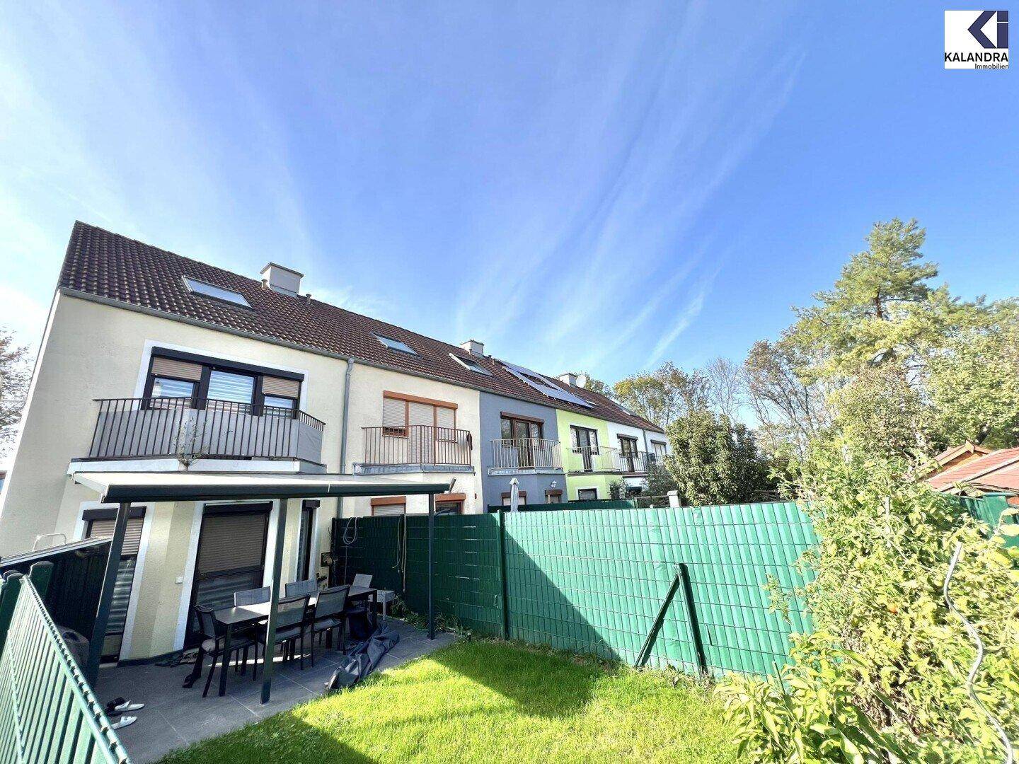 Gepflegter Garten mit überdachter Terrasse und Blick auf die benachbarten Reihenhäuser.
