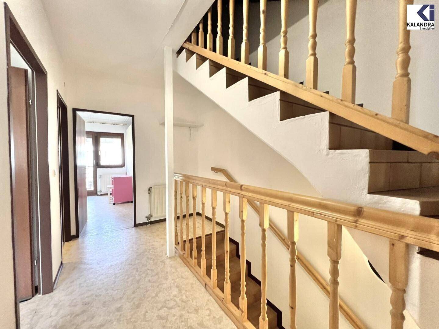 Heller Flur mit Holztreppe und Zugang zu weiteren Räumen im Haus.