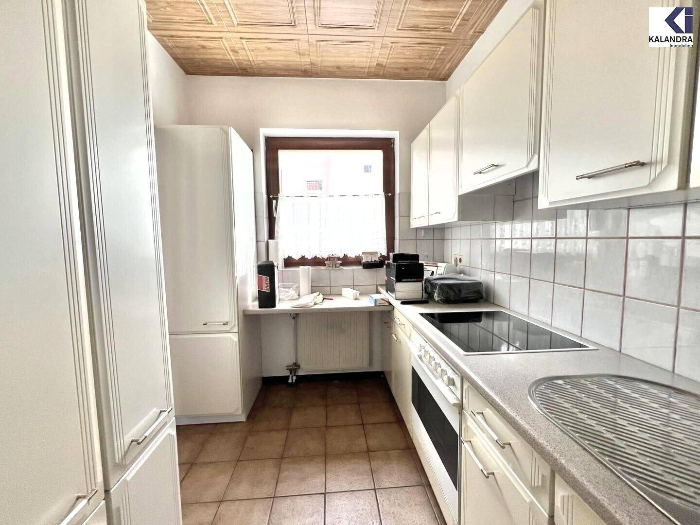 Funktionale Küche mit cremefarbenen Schränken, Spüle, Herd und Kühlschrank.