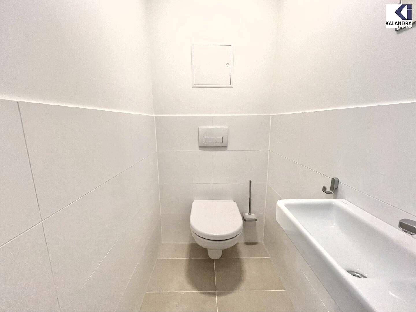 Separates Gäste-WC mit wandhängender Toilette und kleinem Waschbecken.