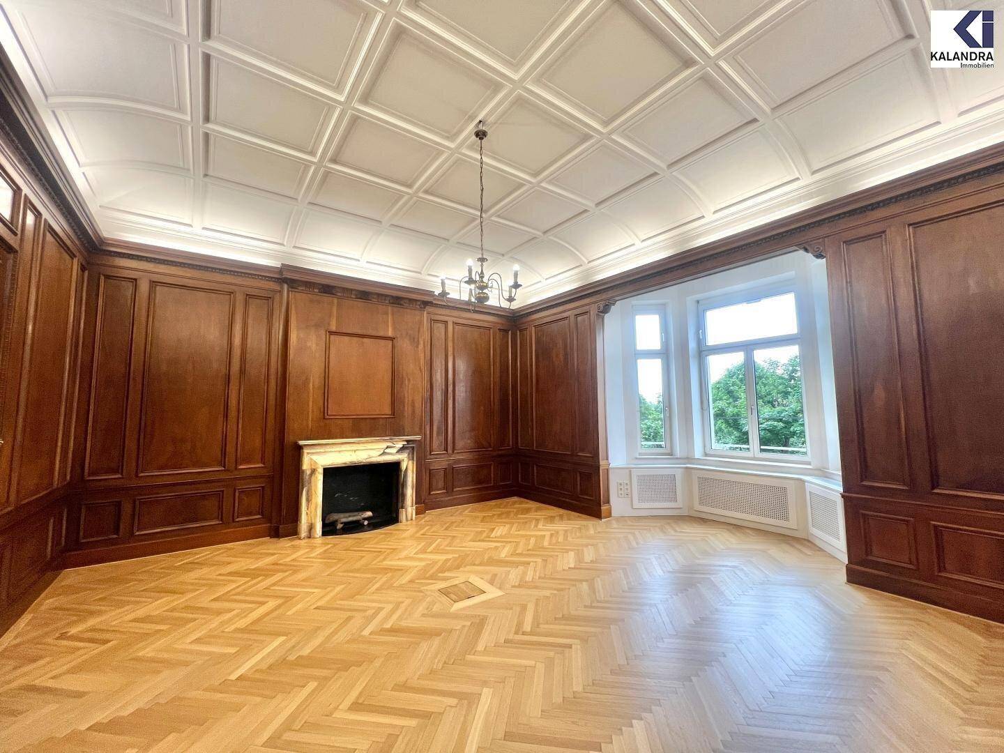 Eleganter Raum mit Holztäfelung, Kamin und Erkerfenster, das einen Blick ins Grüne bietet.