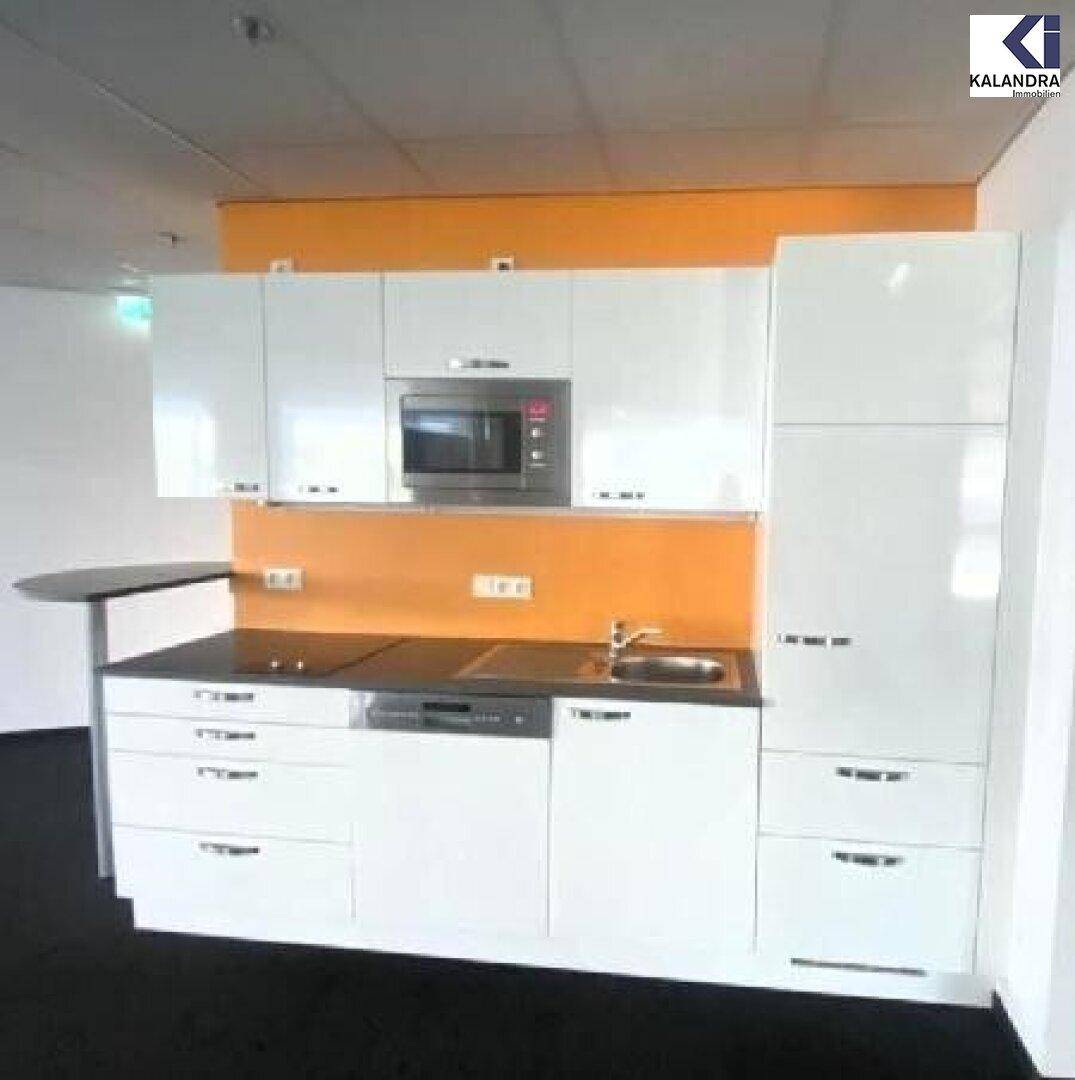 Kompakte, moderne Küchenzeile in Weiß mit integrierten Geräten und orangefarbener Rückwand.