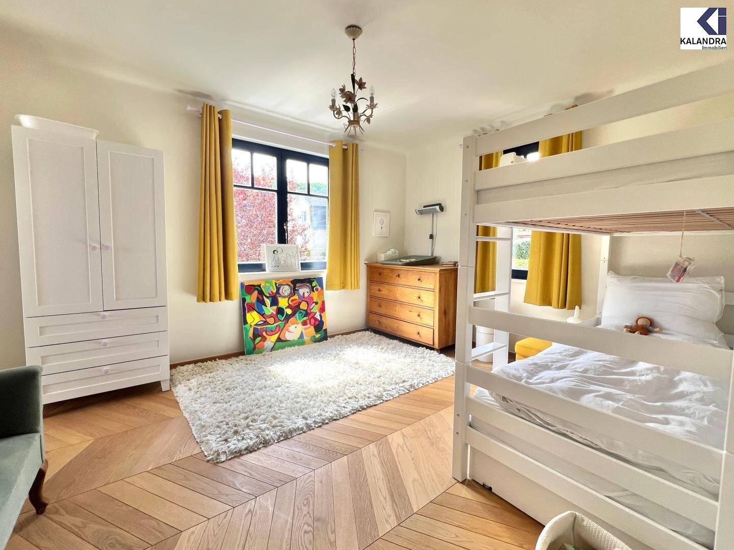 Helles Schlafzimmer mit Etagenbett, weißem Kleiderschrank und elegantem Fischgrätparkett.
