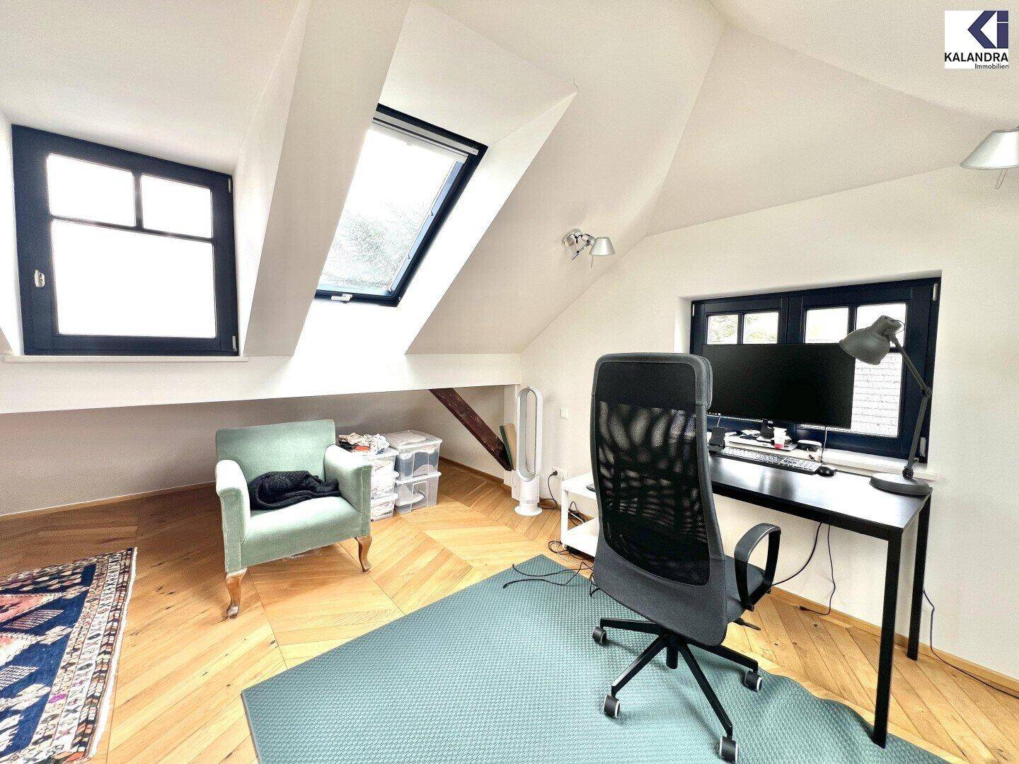Helles Dachgeschossbüro mit Schreibtisch, Dachfenster und Holzboden unter schrägen Decken.