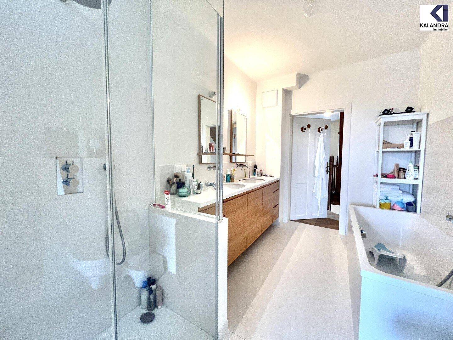 Modernes Badezimmer mit begehbarer Dusche, Badewanne und Doppelwaschbecken in hellem Design.