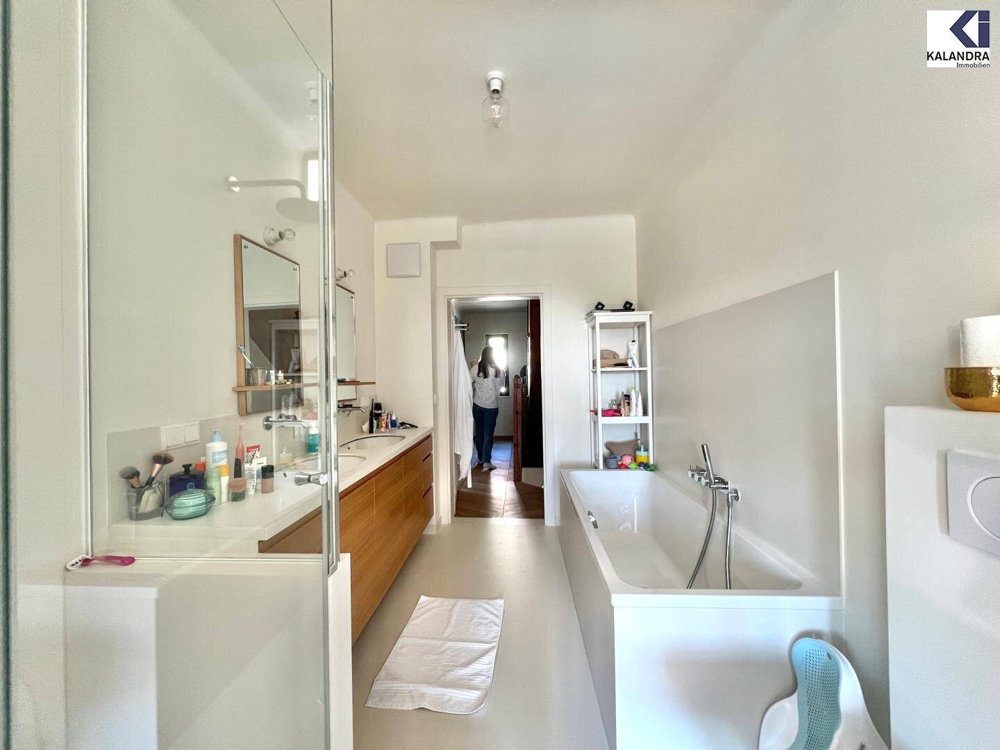 Helles Badezimmer mit Badewanne, Dusche und Doppelwaschbecken in einem modernen Ambiente.