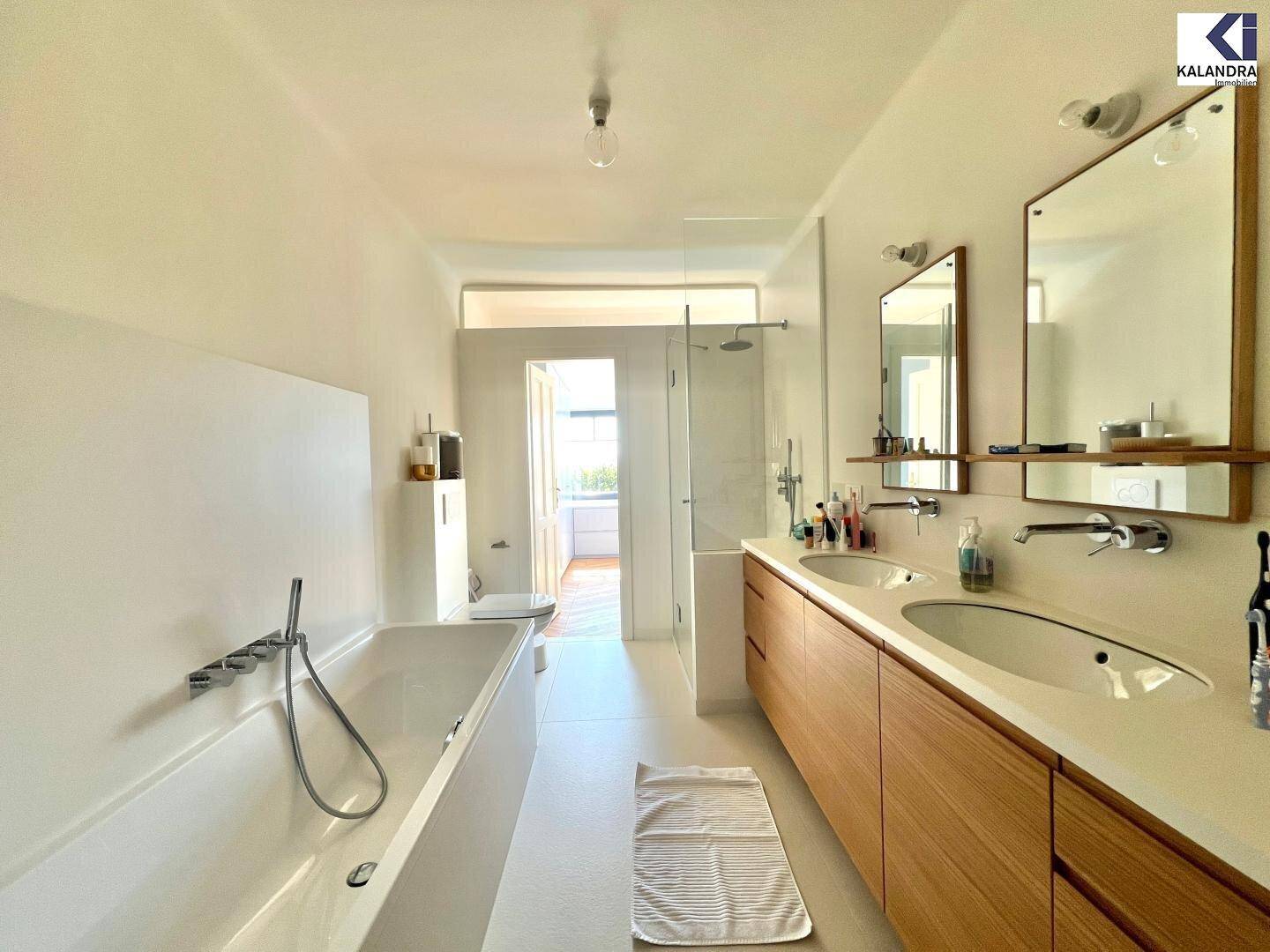 Großes Badezimmer mit Badewanne, Doppelwaschbecken und separater Dusche in modernem Stil.