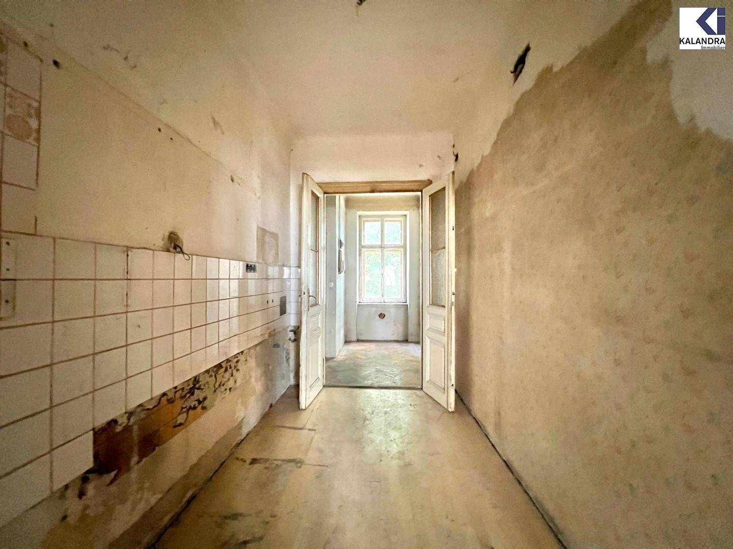 Sanierungsbedürftiger Flur mit alten Fliesen und abblätternder Farbe, der auf eine Renovierung wartet.
