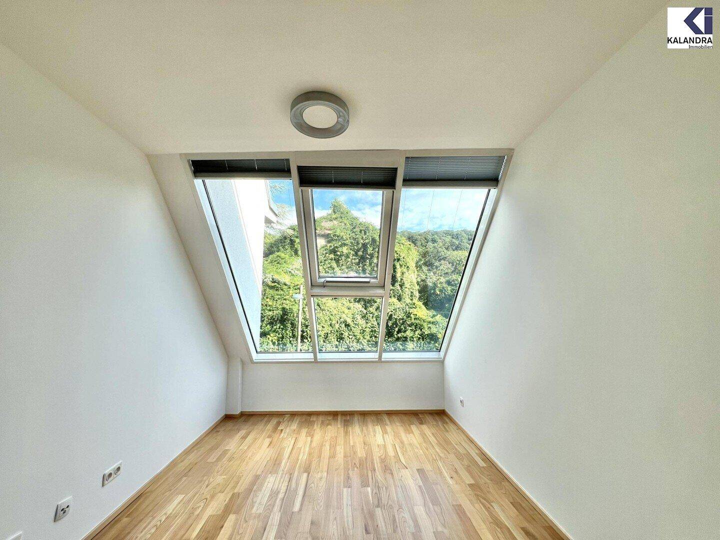 Gemütliches Zimmer im Dachgeschoss mit Holzboden und großen Dachfenstern, die viel Licht spenden.