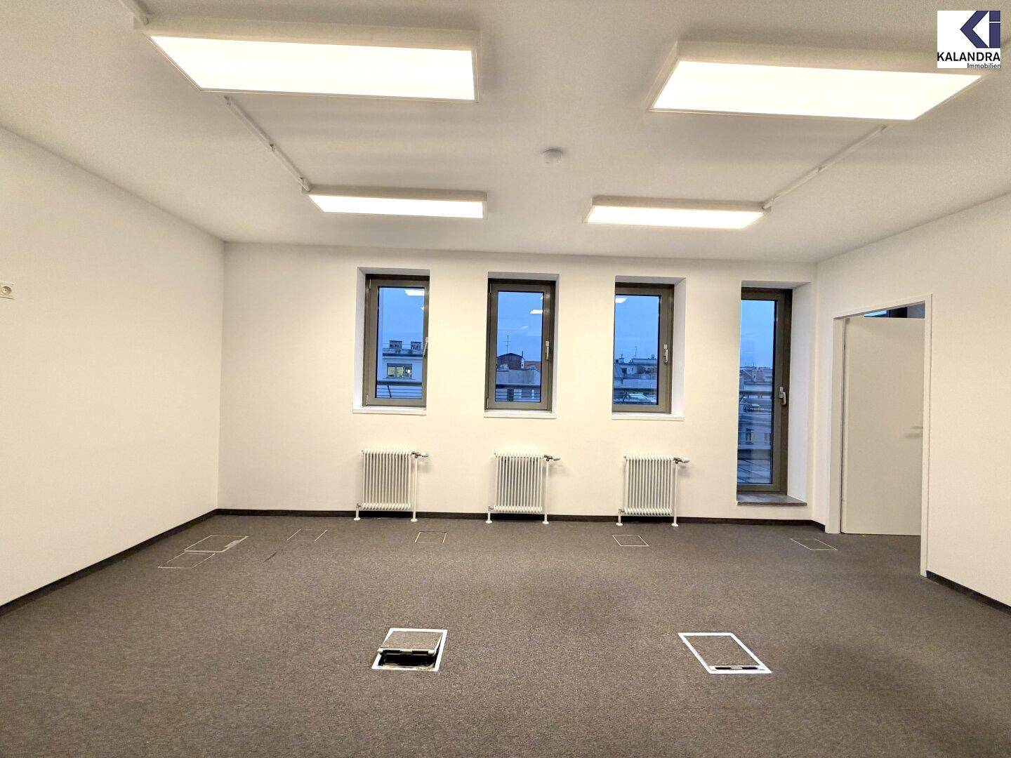 Leerer Büroraum mit Teppichboden, drei Fenstern und Heizkörpern, ideal für individuelle Gestaltung.