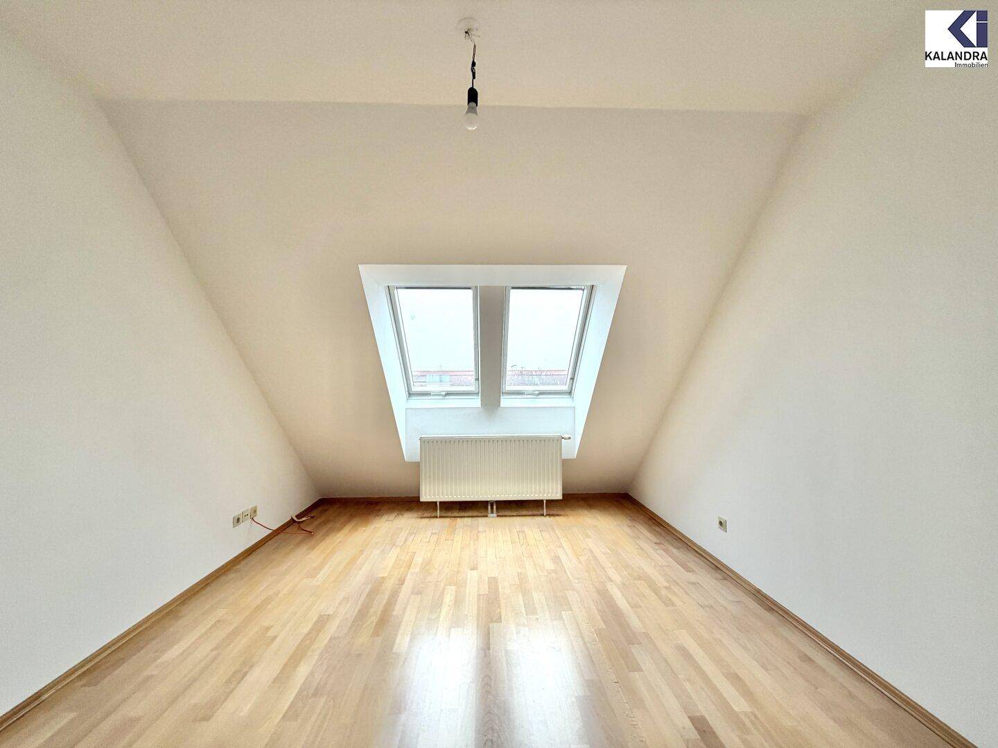 Helles Schlafzimmer im Dachgeschoss mit schrägen Wänden, Parkettboden und Dachfenstern.