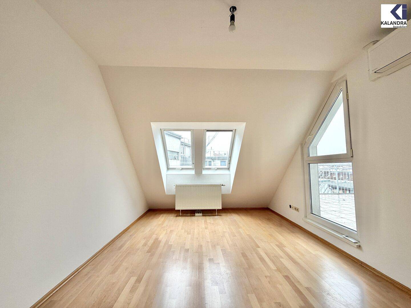 Helles Schlafzimmer im Dachgeschoss mit Parkettboden, Dachfenstern und Klimaanlage.