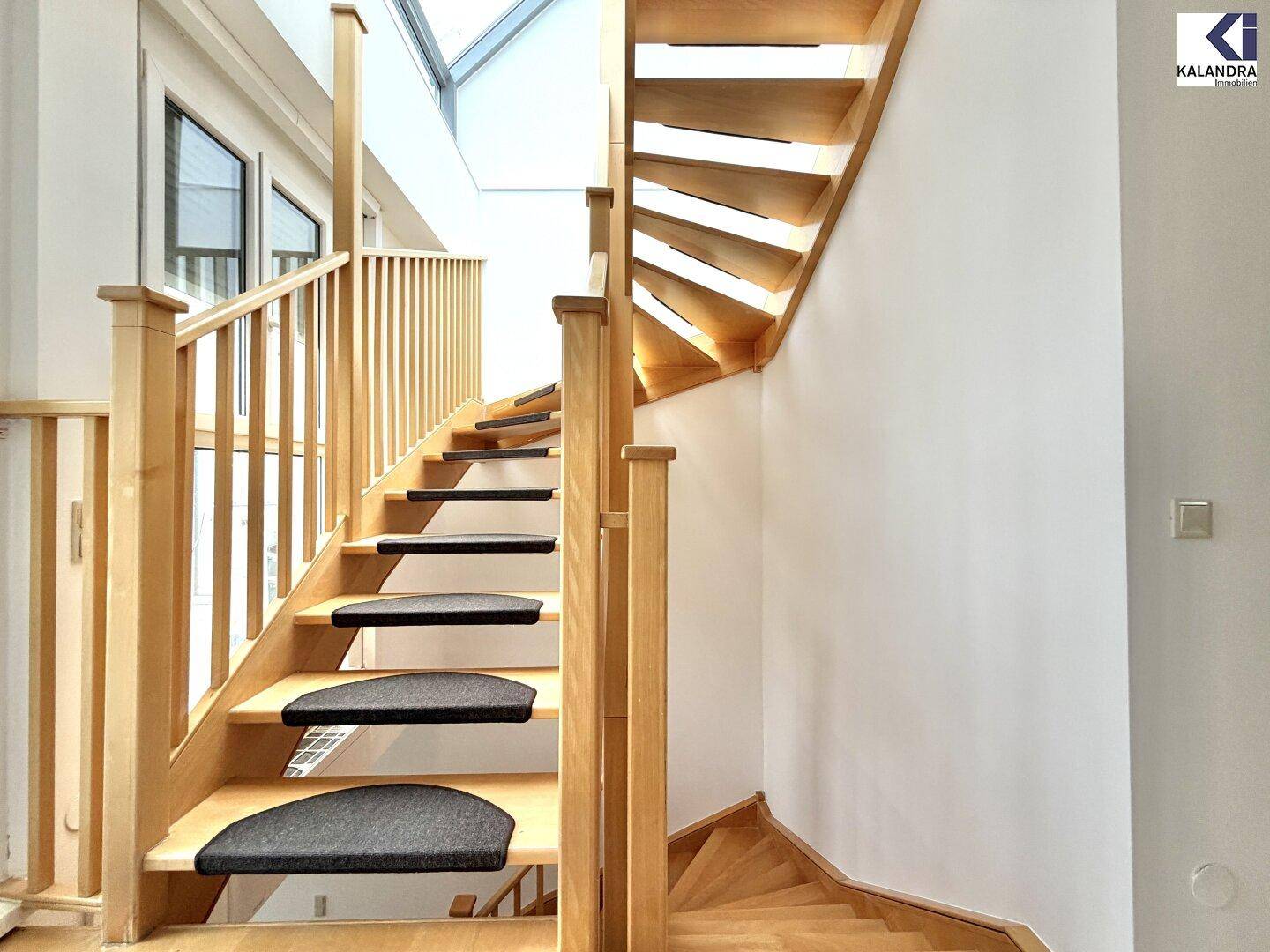 Elegante Holztreppe mit Teppichstufen und einem Oberlicht, das den Bereich erhellt.