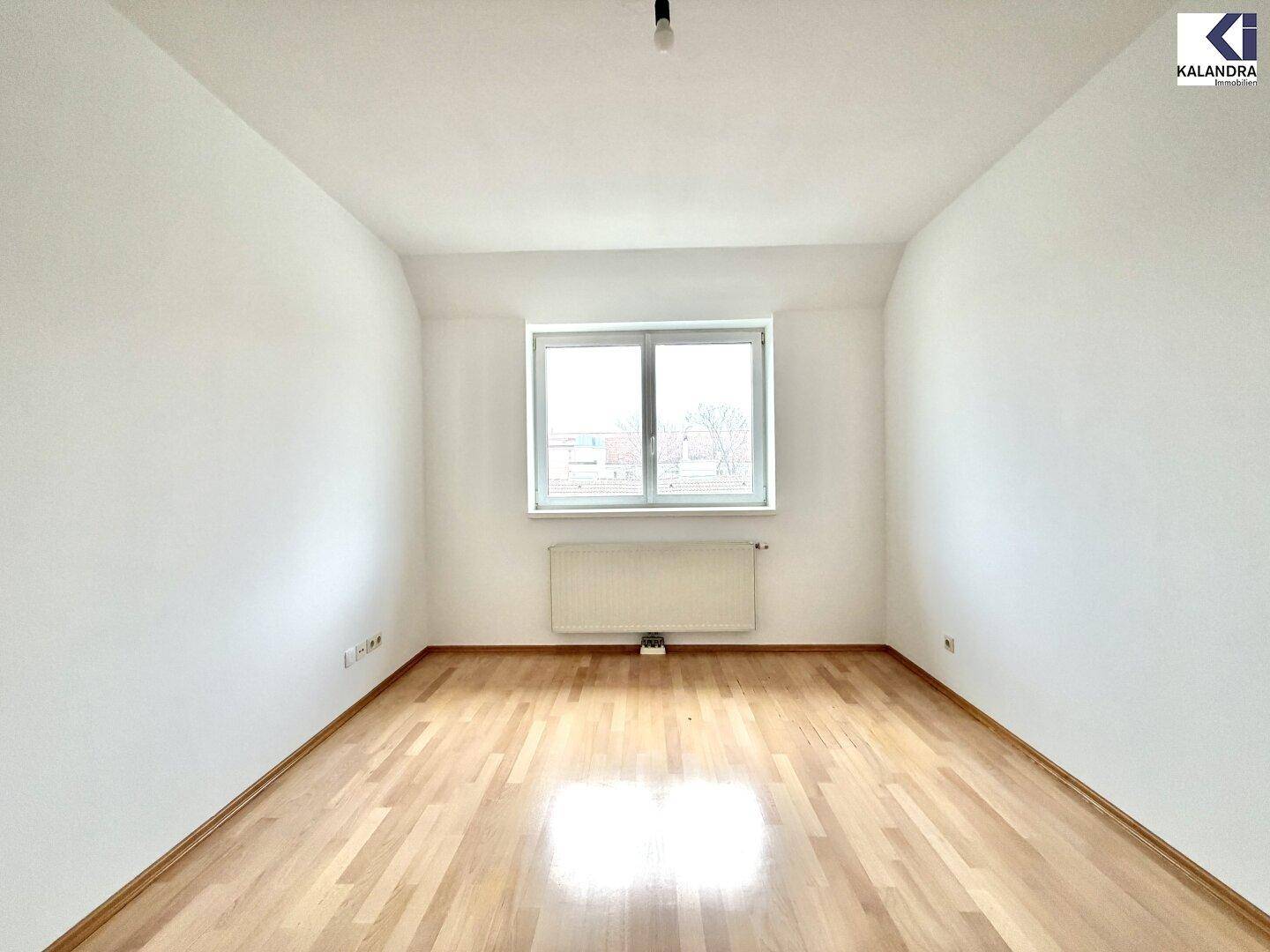 Gemütliches Schlafzimmer mit Parkettboden, weiß gestrichenen Wänden und einem großen Fenster.