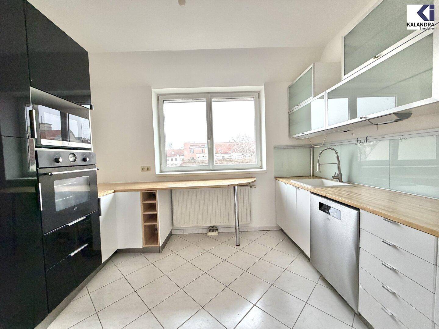 Funktionale Küche mit weißen und schwarzen Schränken, Holzarbeitsplatte und integriertem Geschirrspüler.