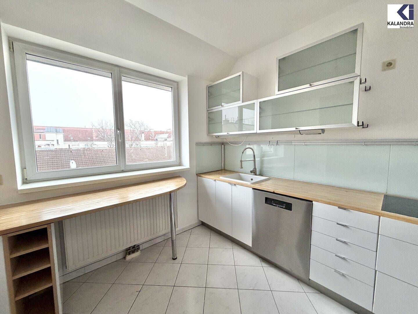 Moderne Küche mit weißen Schränken, Holzarbeitsplatte, Spüle und integriertem Geschirrspüler.