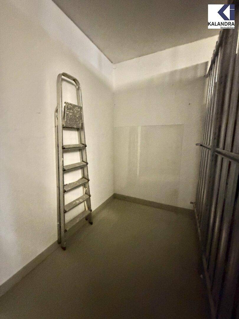 Leerer Abstellraum mit Metallabtrennung und einer Leiter, ideal für Lagerzwecke.