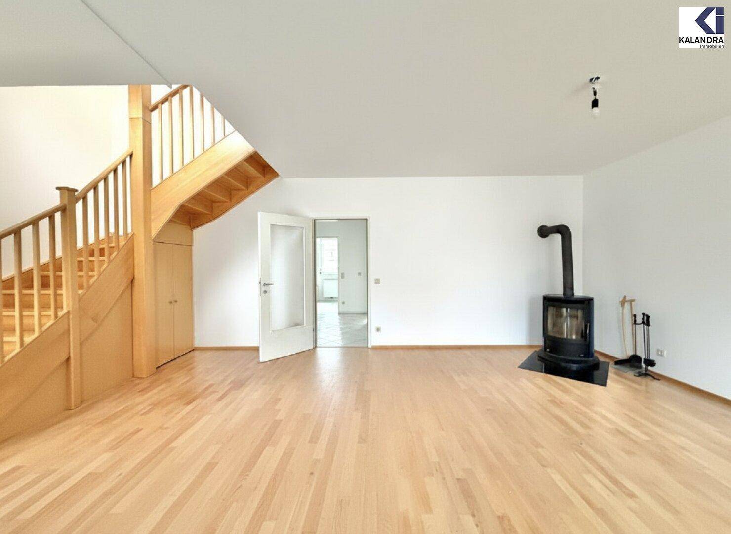 Geräumiges Wohnzimmer mit Holztreppe und modernem Holzofen, bereit zur individuellen Gestaltung.