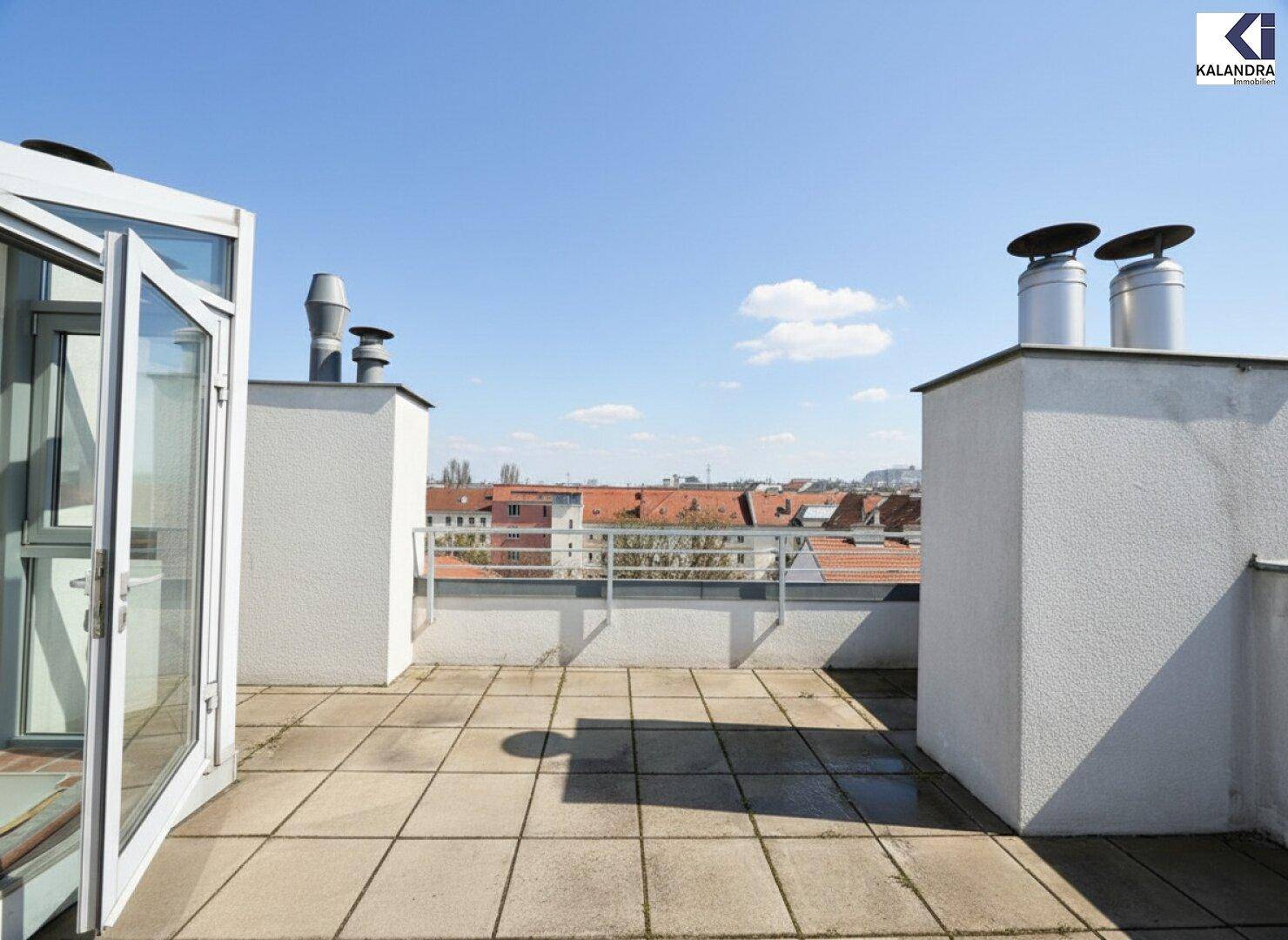 Sonniger Terrassenbereich mit Fliesenboden und Zugang zu einem Innenraum, umgeben von Stadtansichten.