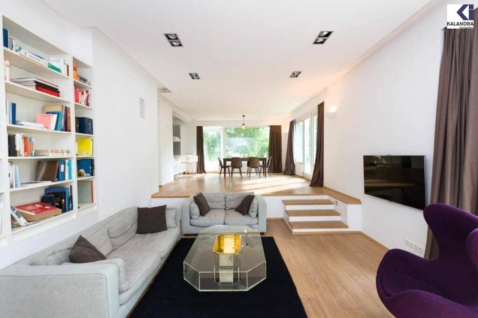 Helles, offenes Wohn- und Esszimmer mit Parkettboden und großen Fenstern zum Garten.