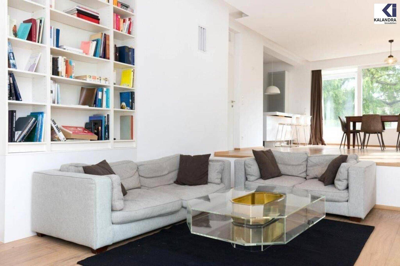 Geräumiges Wohnzimmer mit integriertem Bücherregal und offenem Übergang zum Essbereich.