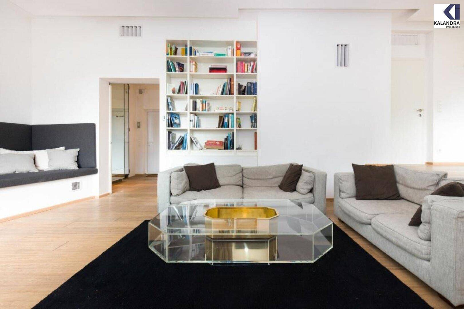 Gemütlicher Wohnbereich mit großem Sofa, Bücherregal und Sitzbank am Fenster.