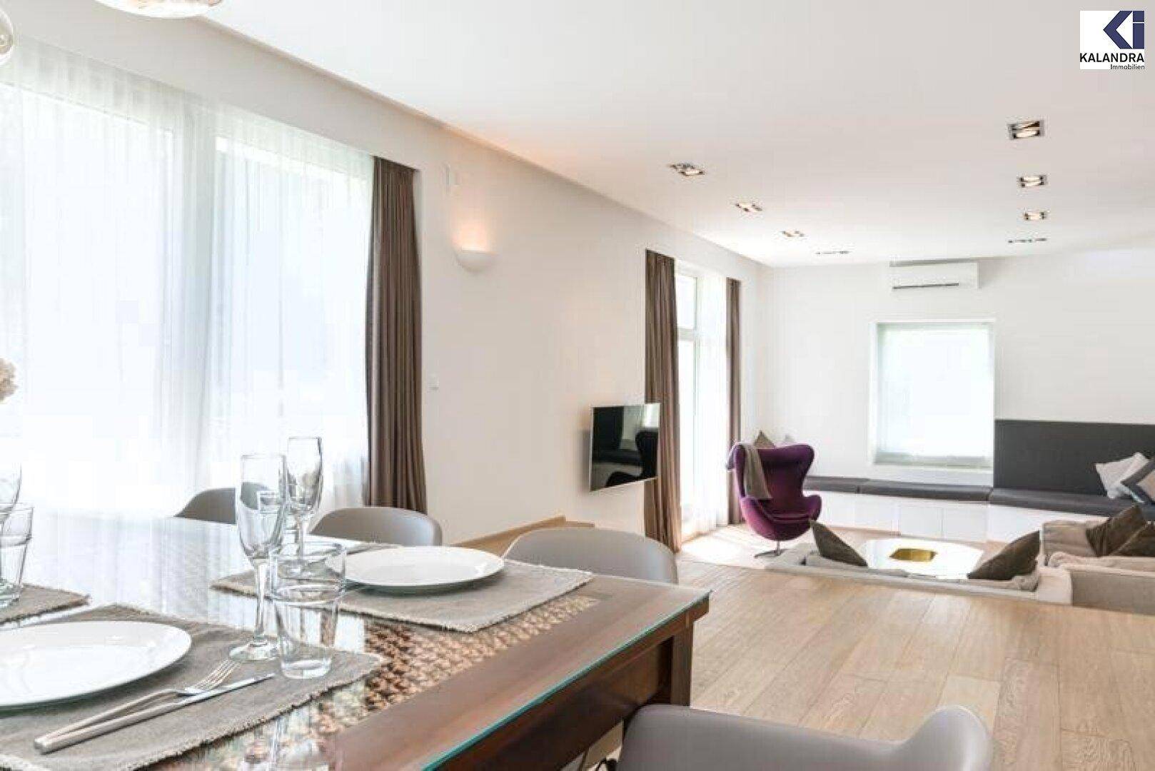 Heller Essbereich mit großem Tisch und offenem Übergang zum Wohnzimmer mit Gartenblick.