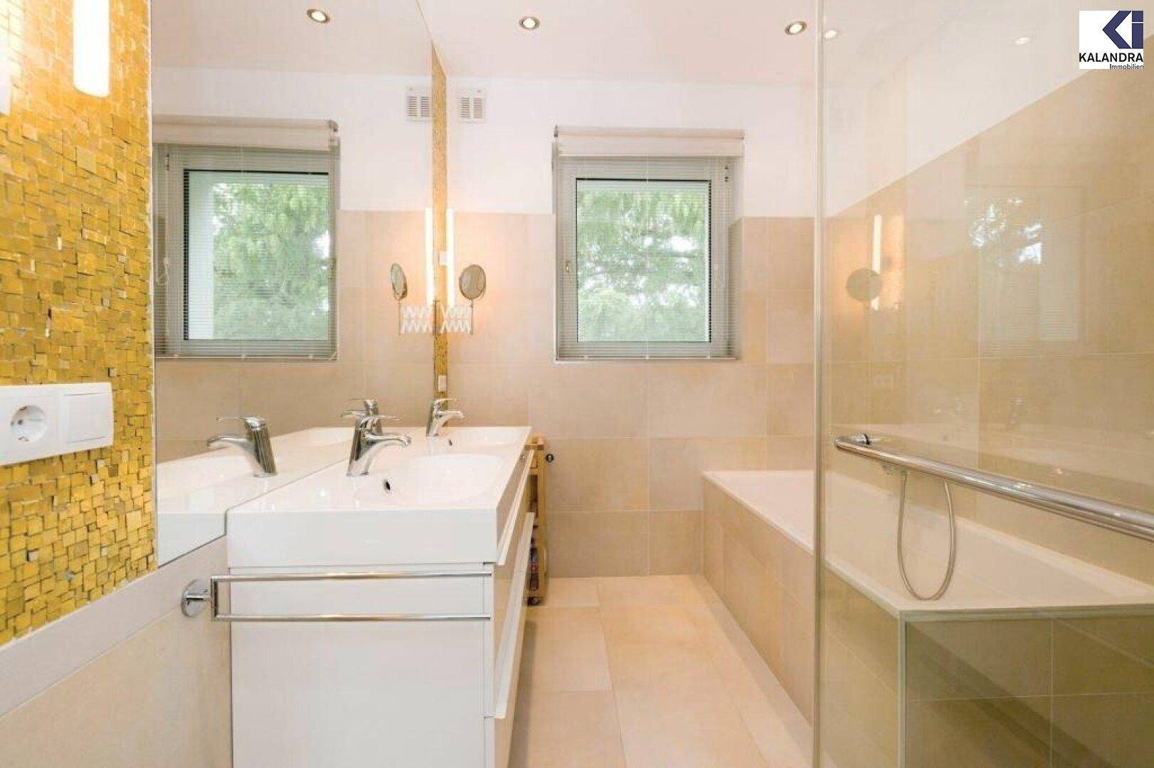 Modernes Badezimmer mit Doppelwaschbecken, Badewanne und Fenster.