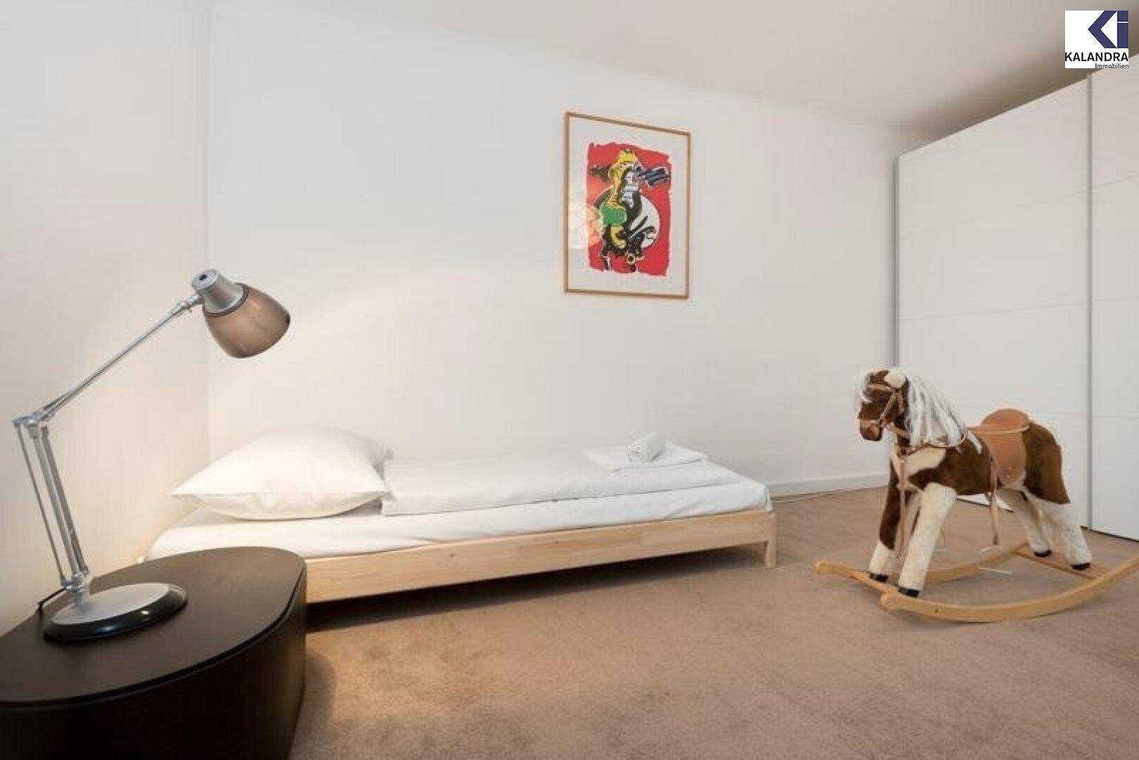 Kinderzimmer mit Einzelbett, Schaukelpferd und Teppichboden.