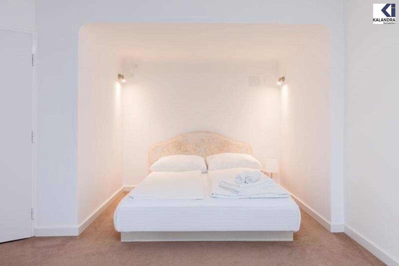 Gemütliches Schlafzimmer mit Doppelbett in einer Nische und Teppichboden.
