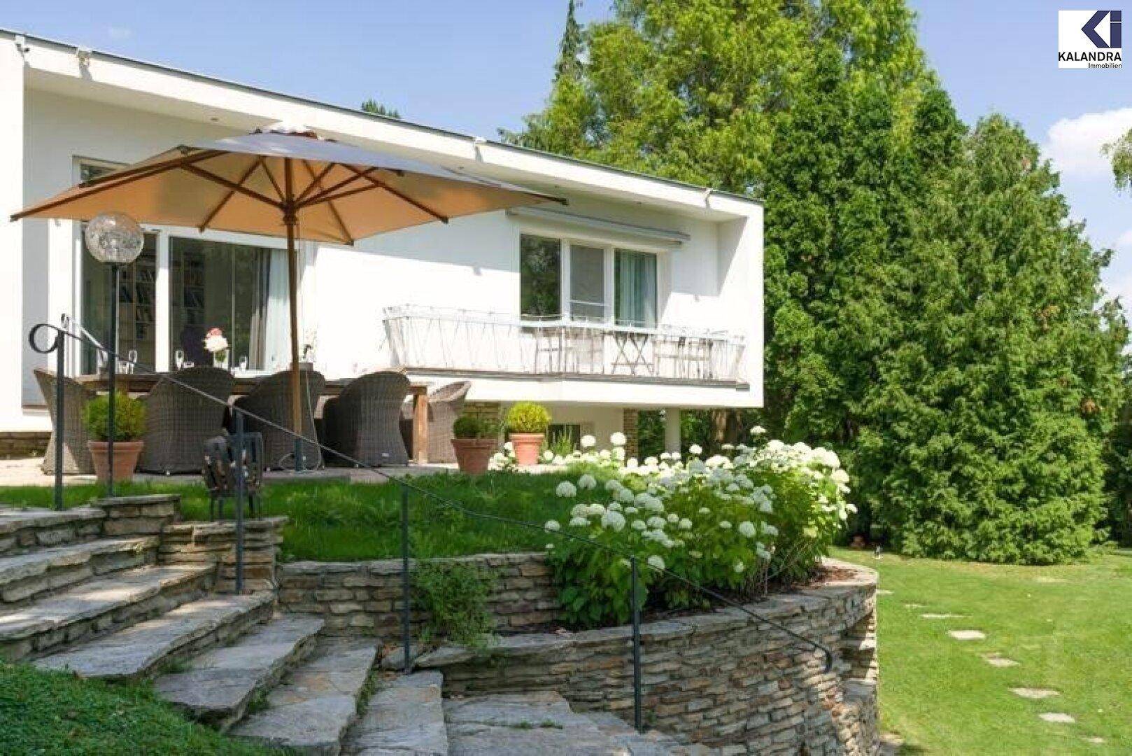 Modernes Haus mit Terrasse, Steintreppe und blühenden Hortensien im Garten.