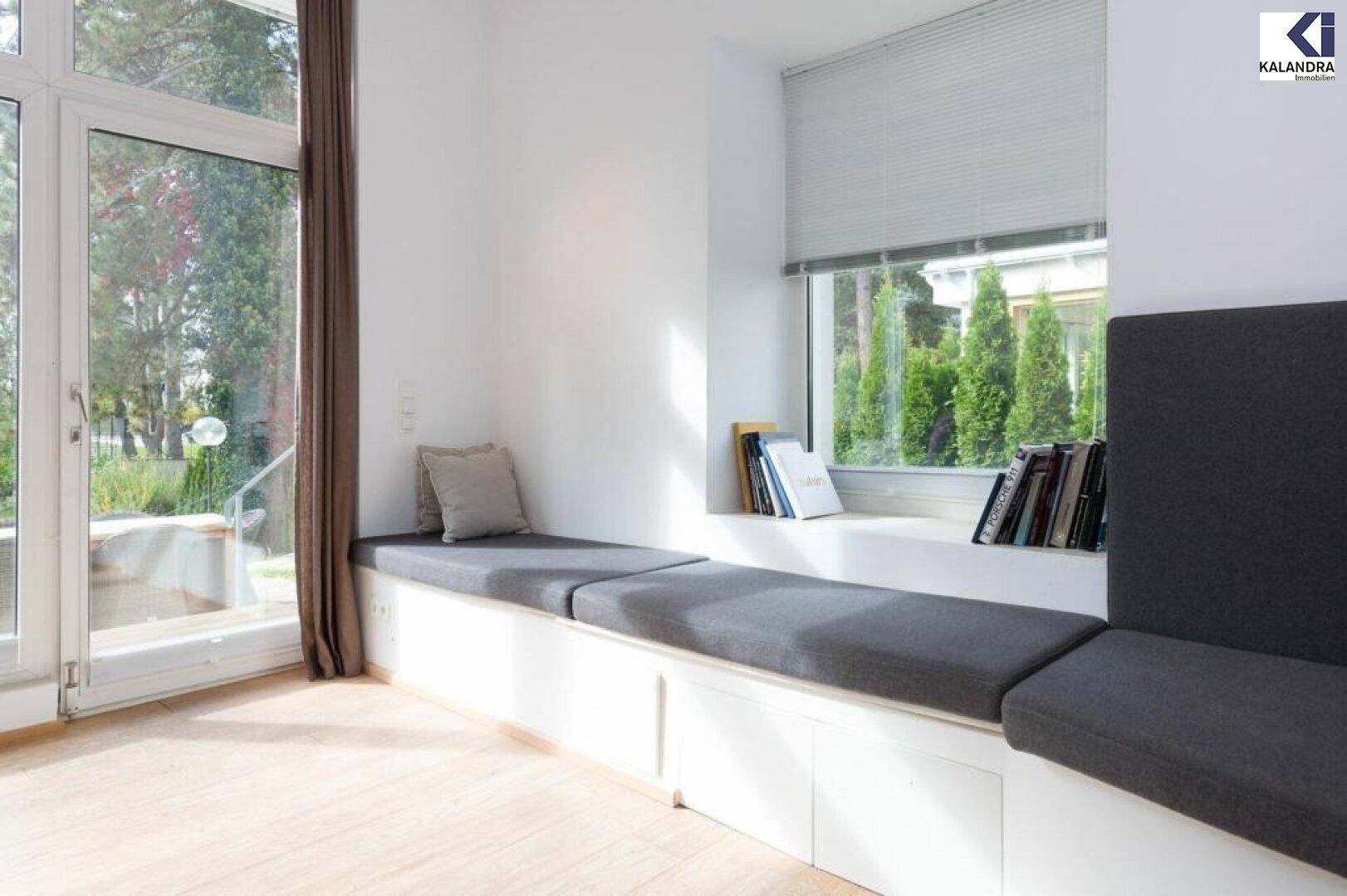 Gemütliche Sitzbank am Fenster mit Kissen und Blick ins Grüne.