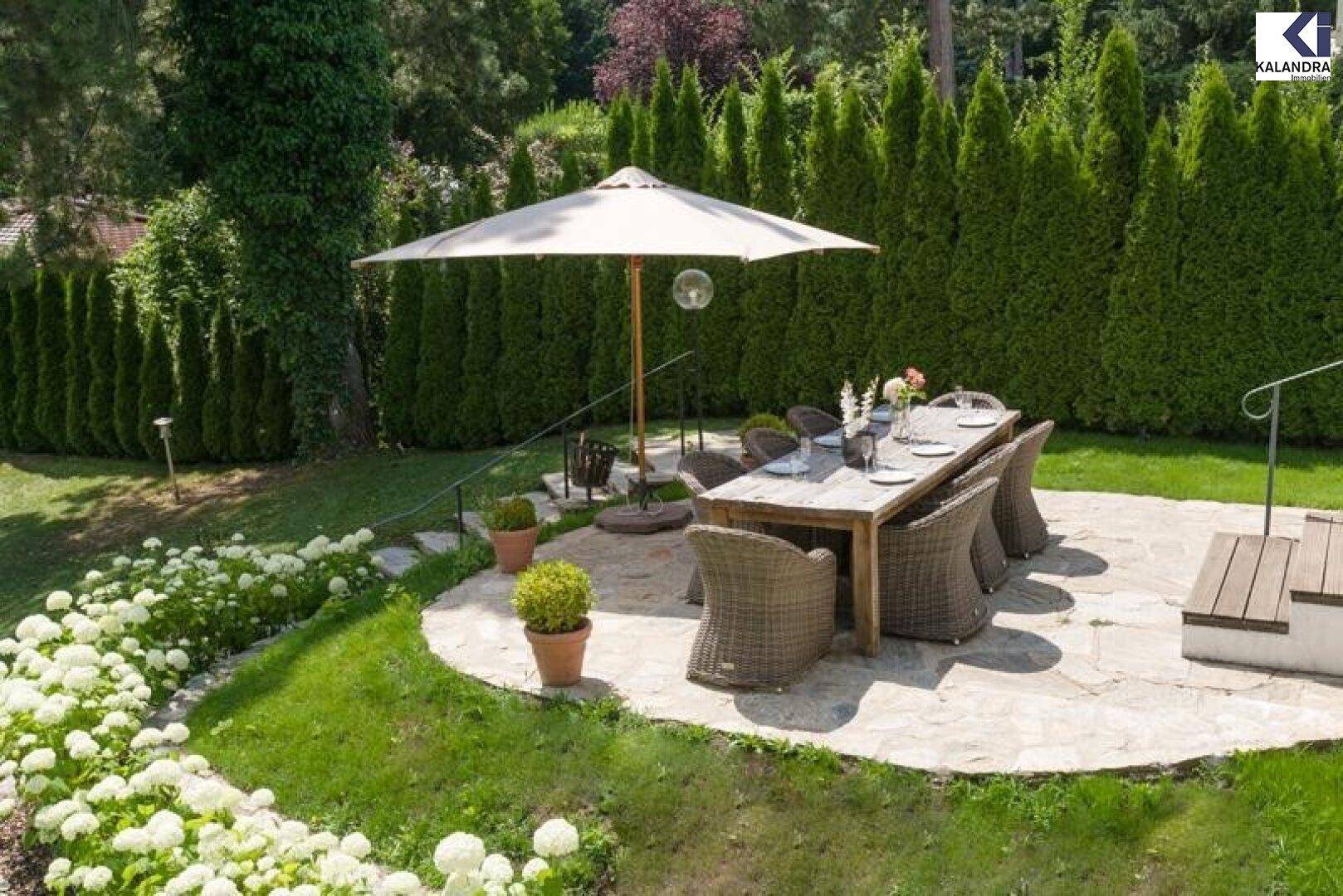 Gedeckter Essbereich auf der Terrasse mit Rattanmöbeln und Blick auf den Garten.