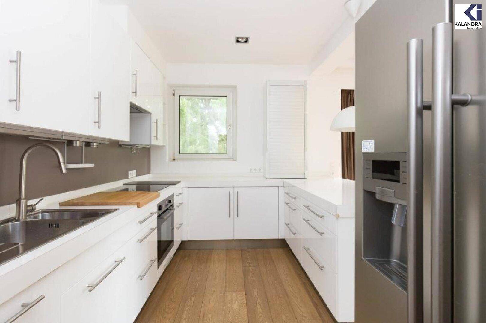 Moderne weiße Küche mit Hochglanzfronten, integrierten Geräten und Parkettboden.
