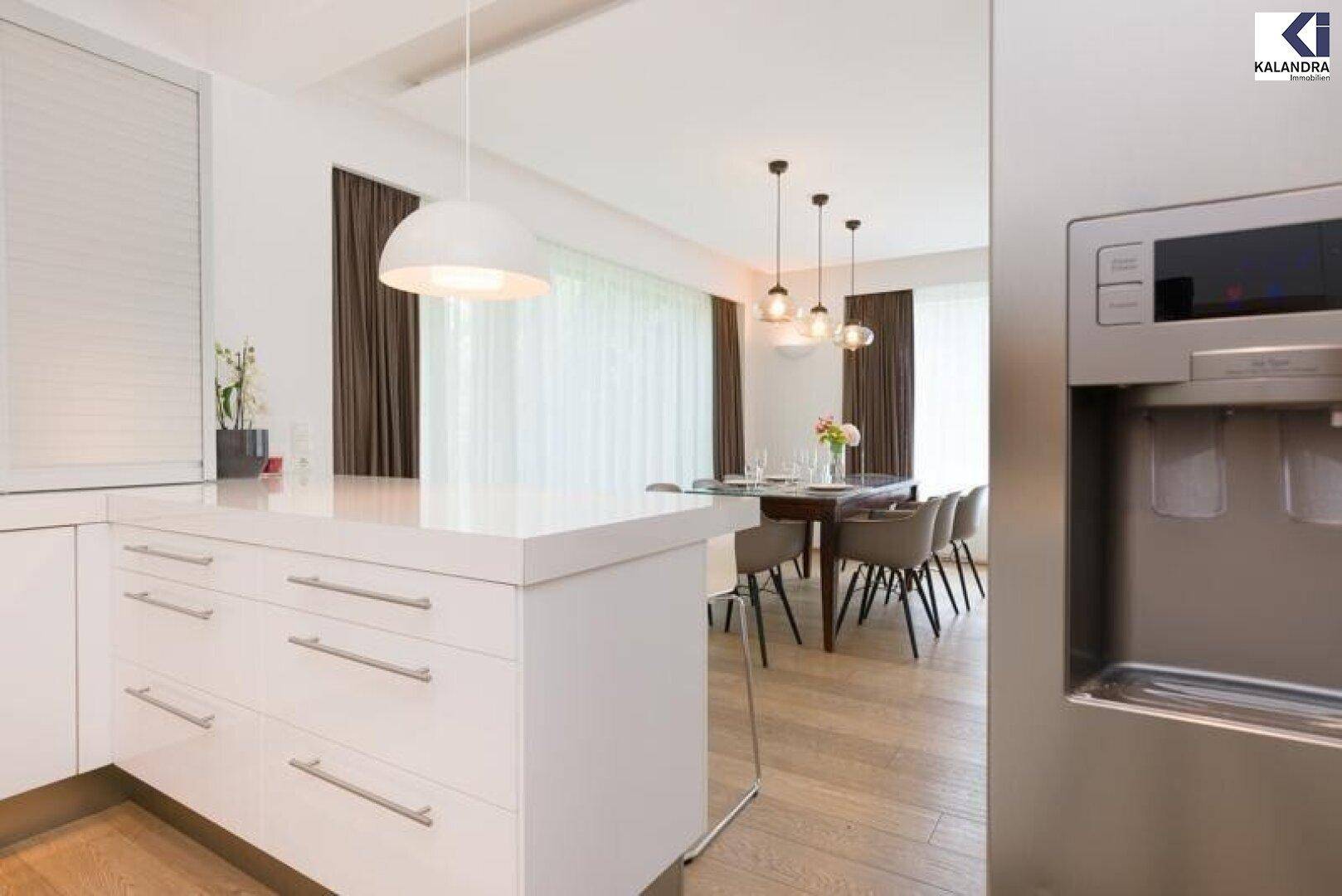 Moderne weiße Küche mit Kochinsel und Blick auf den Essbereich.