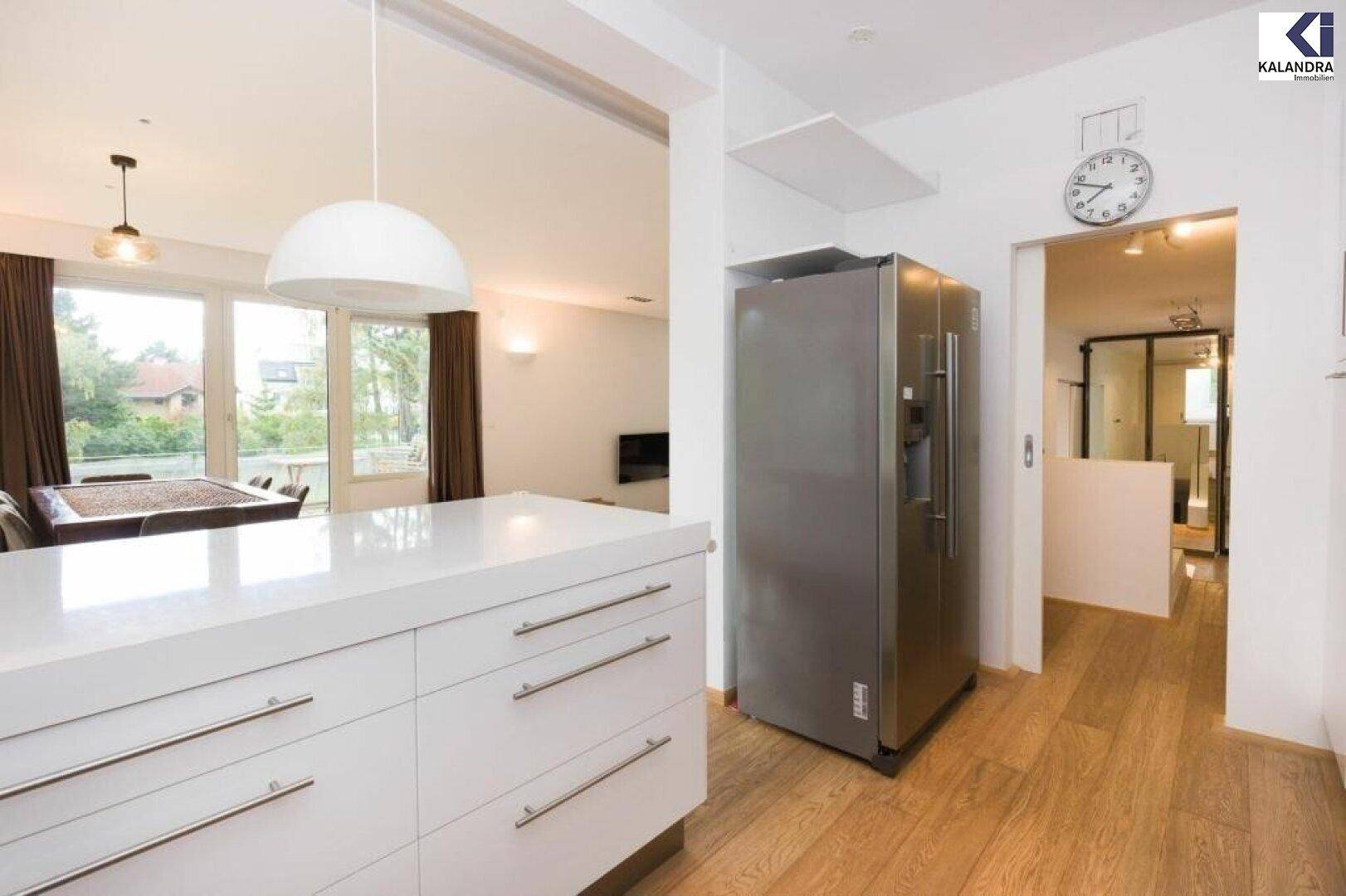 Moderne Küche mit großem Kühlschrank und offenem Übergang zum Flur.