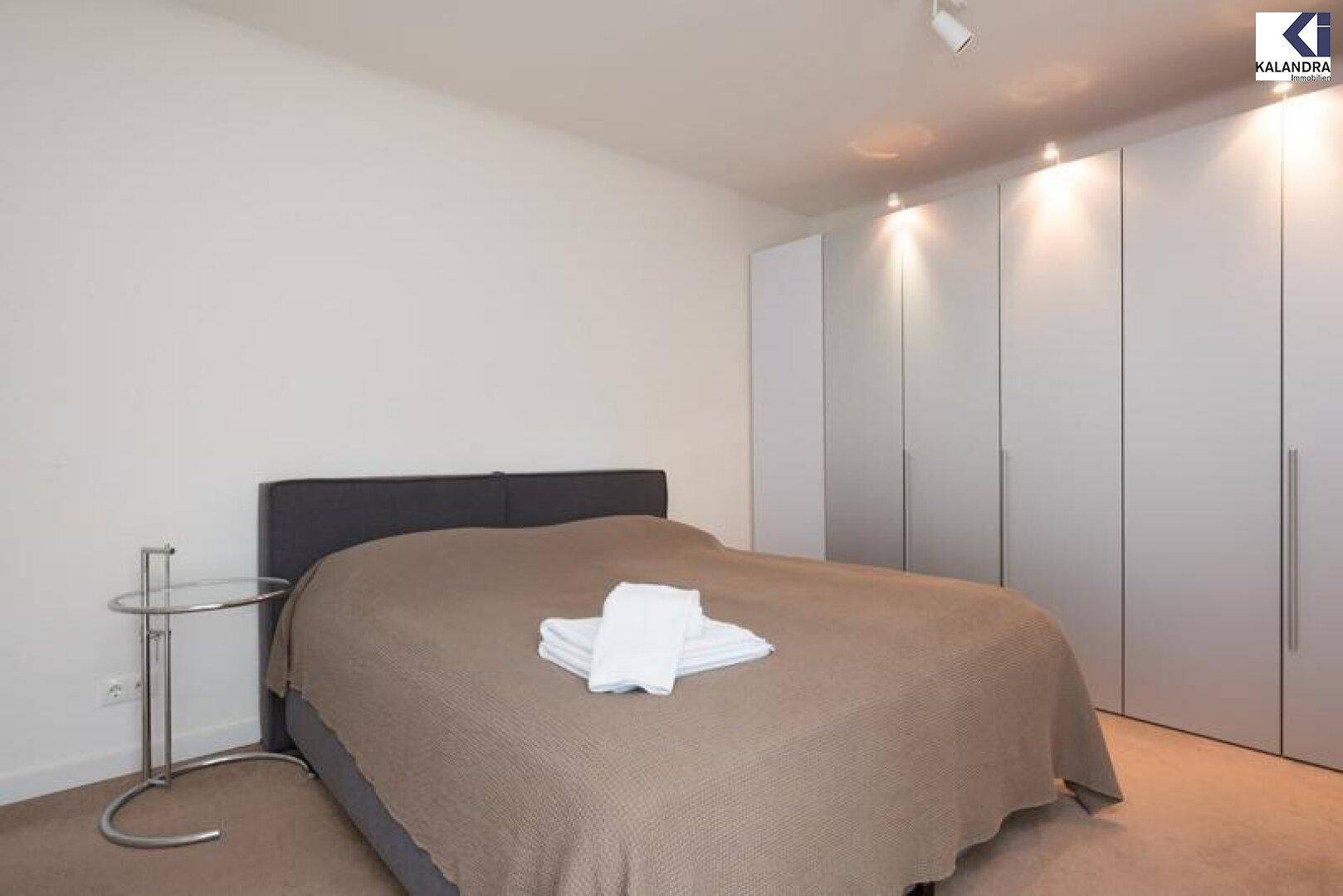Schlafzimmer mit Doppelbett, Einbauschränken und Teppichboden.