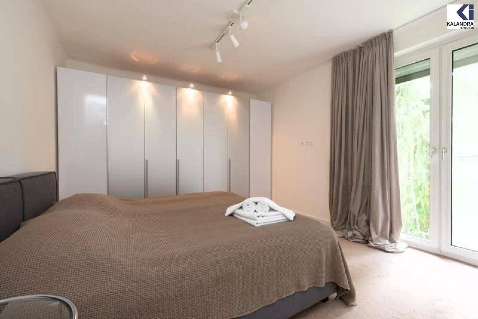 Schlafzimmer mit Doppelbett, Einbauschränken und Zugang zum Garten.